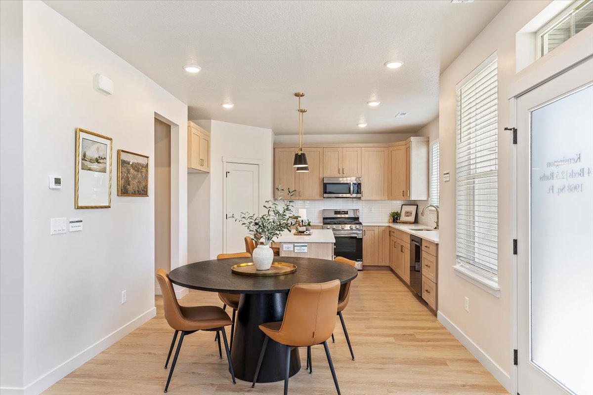 Bright kitchen and dining area featuring wood-finish flooring, recessed lighting, and a kitchen island with pendant lighting