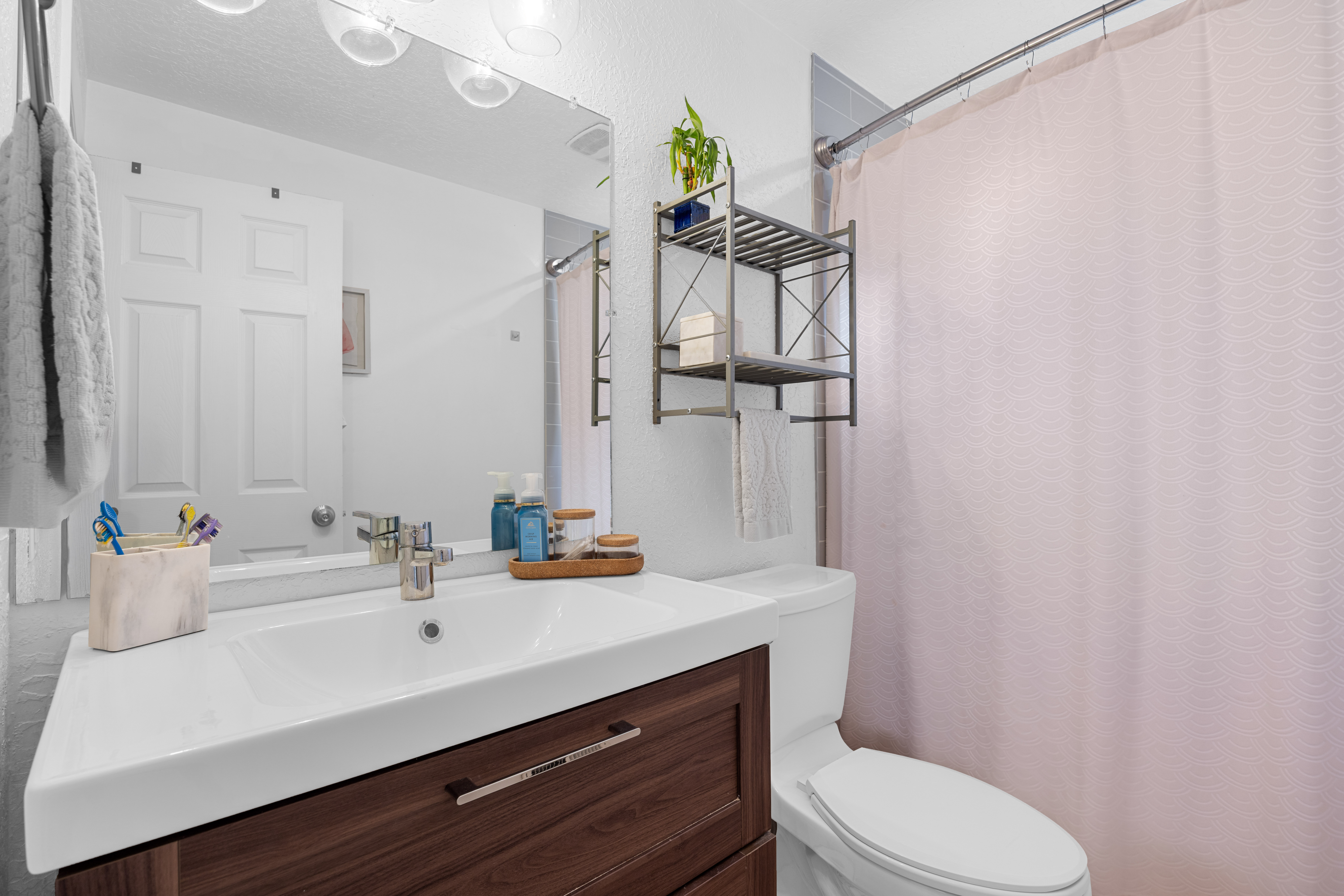 Contemporary bathroom featuring a dark wood-finish vanity with an integrated white sink, a polished chrome faucet, and a large wall-mounted mirror