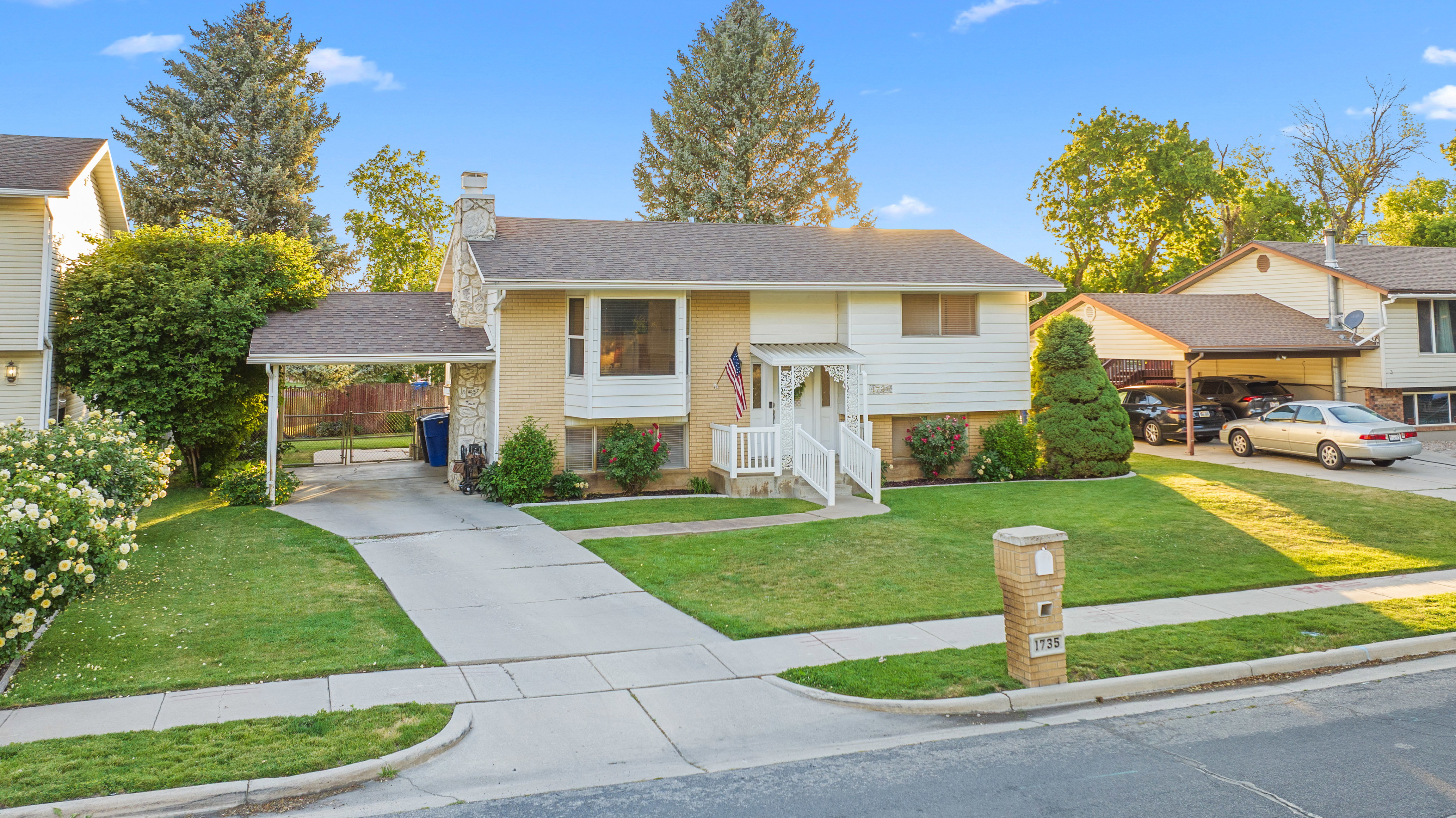 Split-level home featuring brick and siding exterior, a covered carport, and a second driveway with additional covered parking