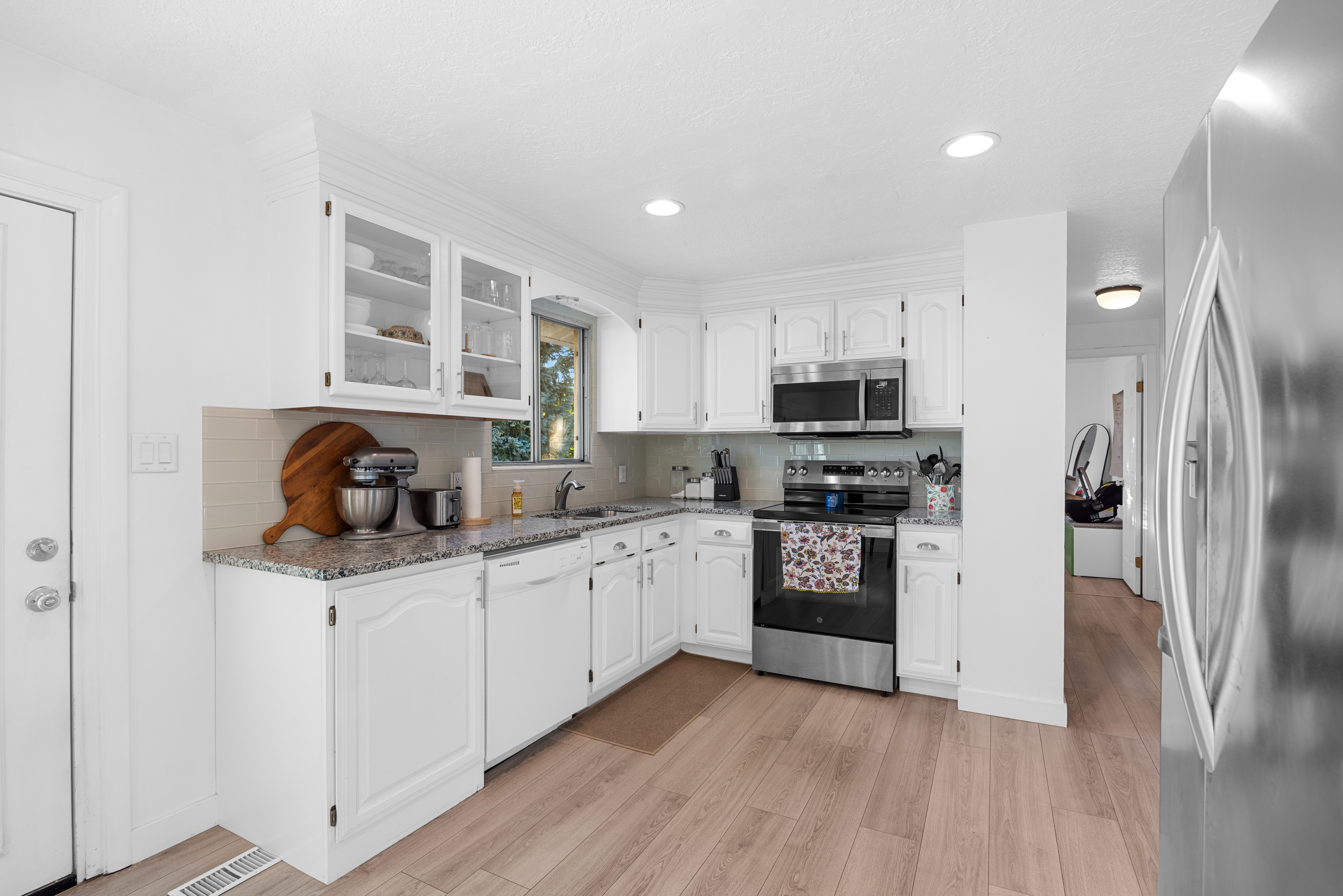 Kitchen featuring white cabinetry with some glass-front uppers, light-toned wood-finish flooring, and recessed lighting