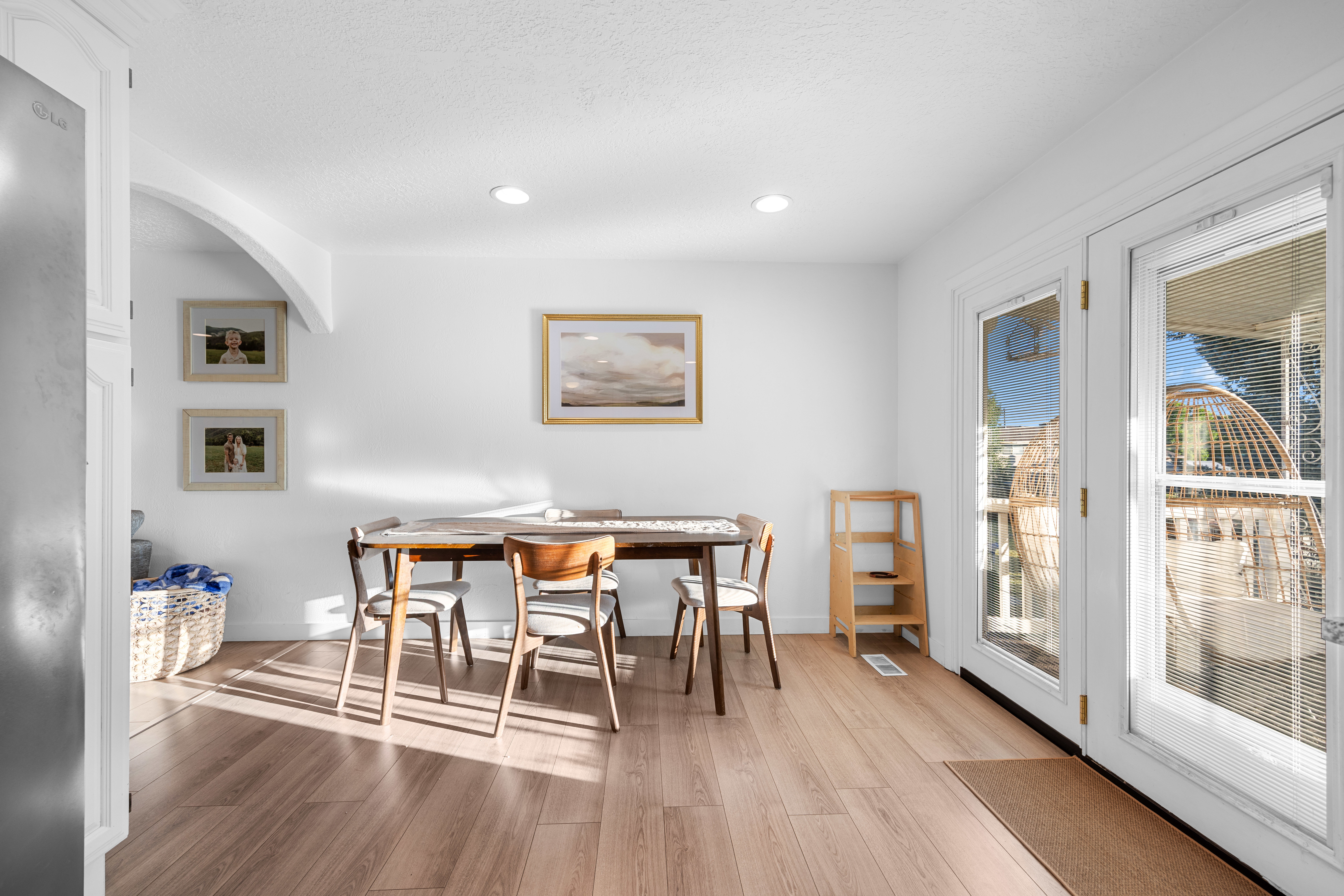 Dining area featuring wood-finish flooring, white walls, recessed lighting, and double glass-paneled doors with screen inserts