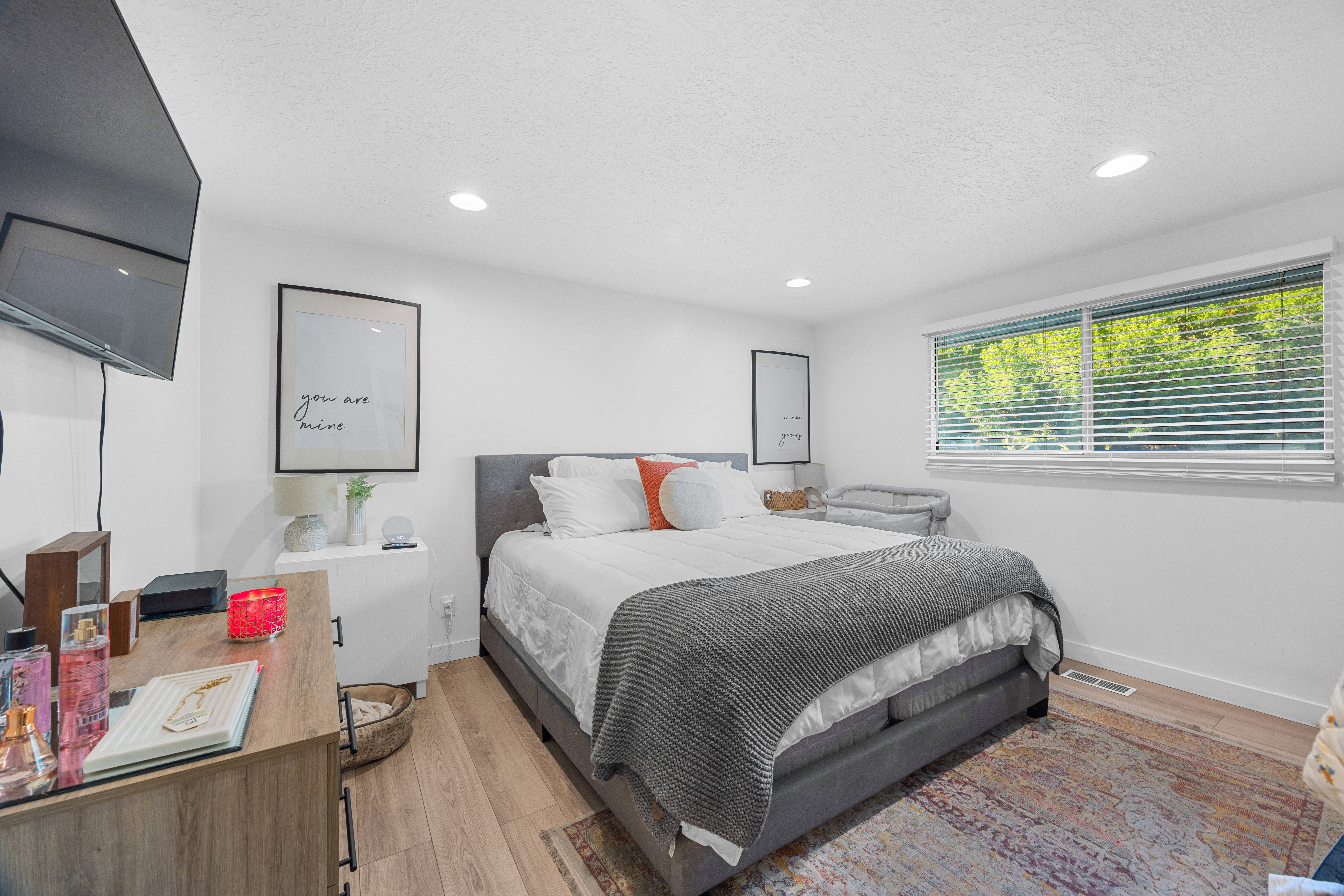 Spacious bedroom featuring light wood-finish flooring, recessed lighting, and a large window with white blinds
