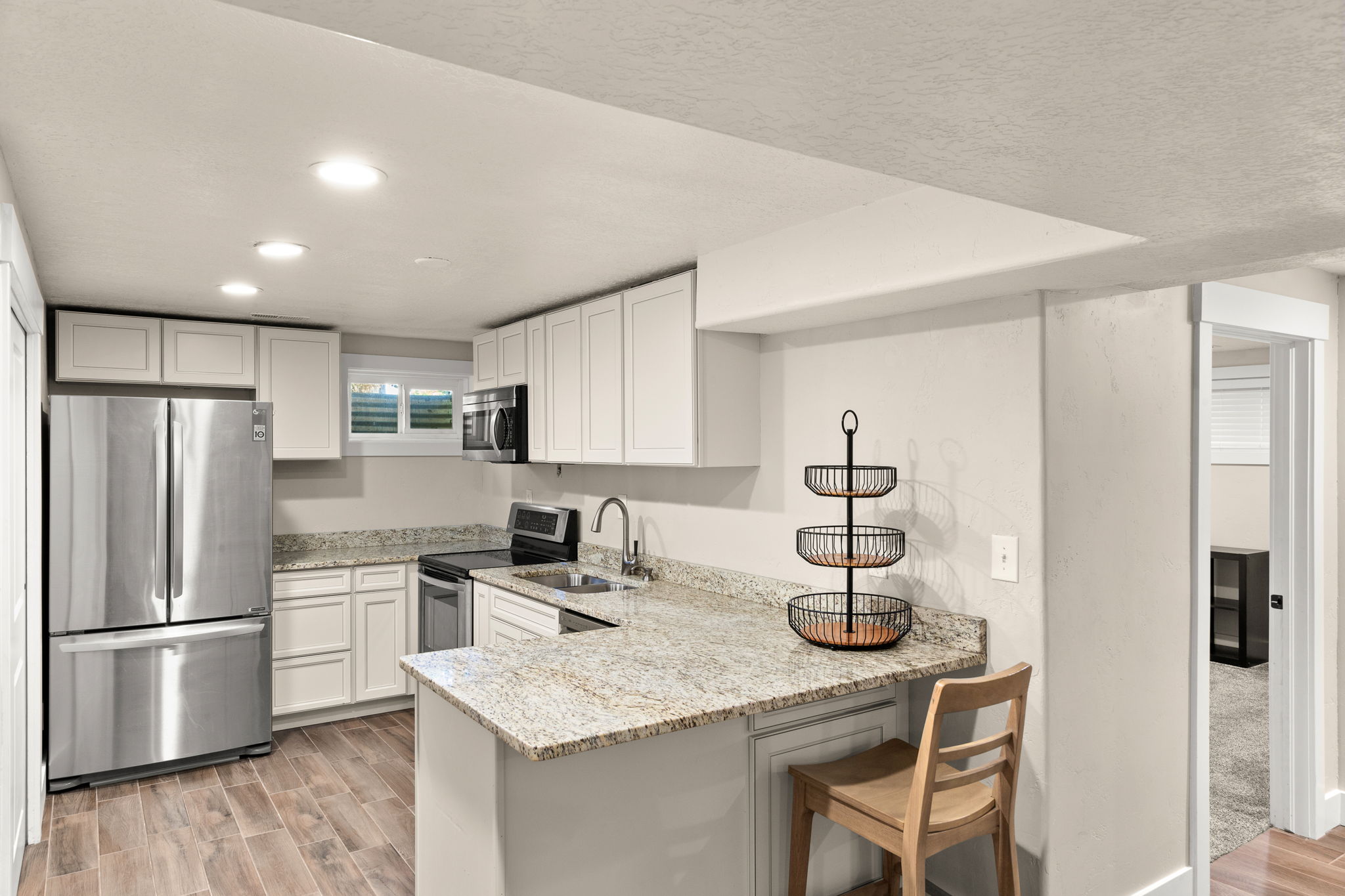 Modern kitchen featuring White cabinetry, Stainless steel appliances, Microwave, Dishwasher, Speckled Stone countertops, and wood-finish flooring!  Large Pantry!