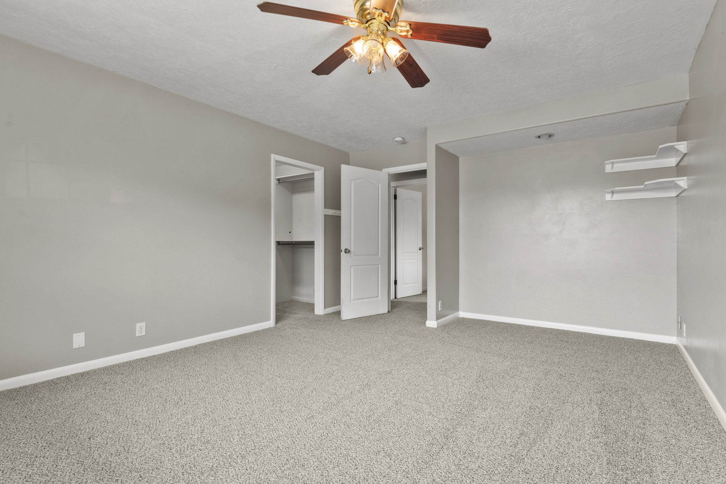 Carpeted room featuring a ceiling fan with light fixture, neutral wall color, and white trim