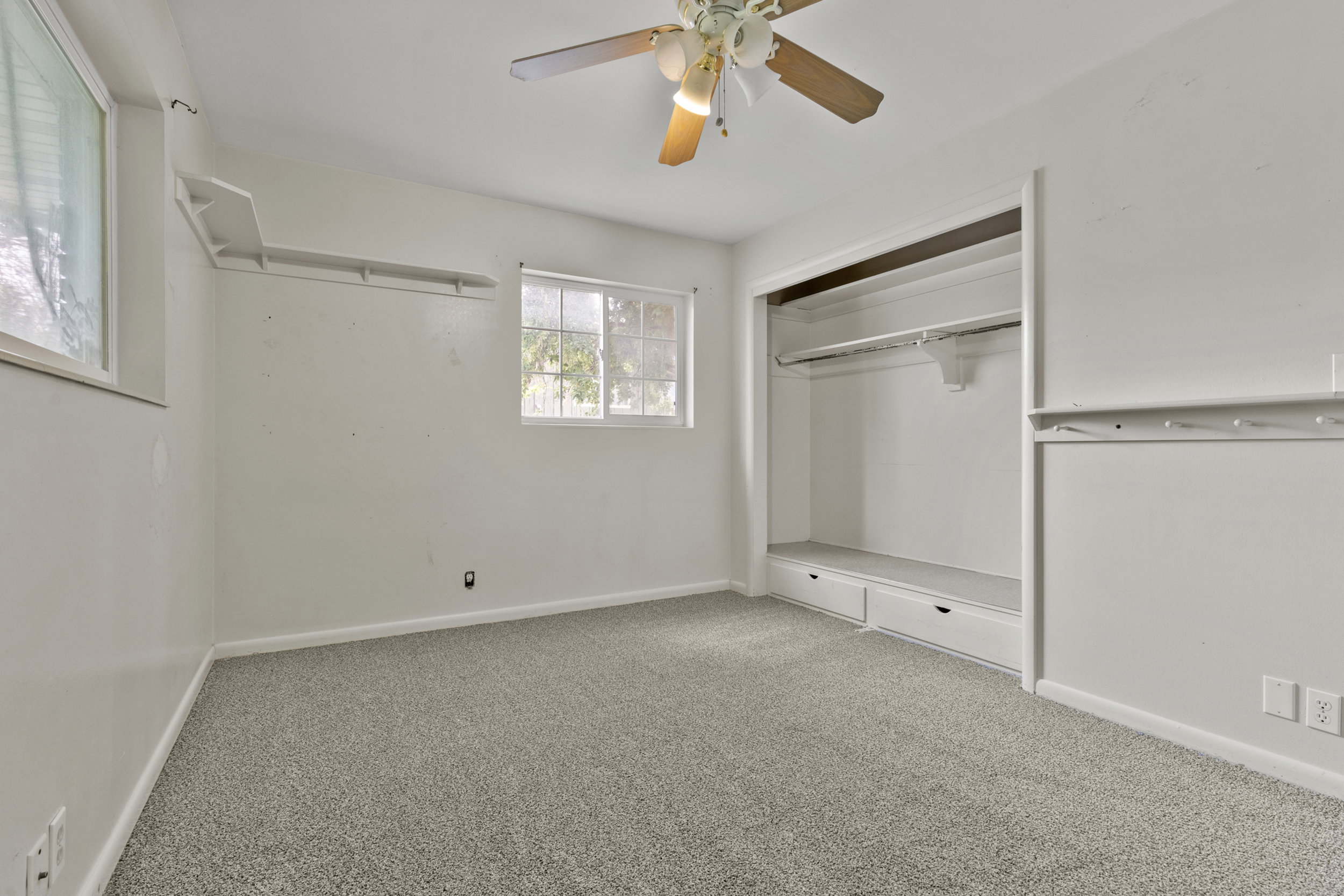 Room featuring light-toned carpet flooring, a ceiling fan with integrated lighting, and white walls