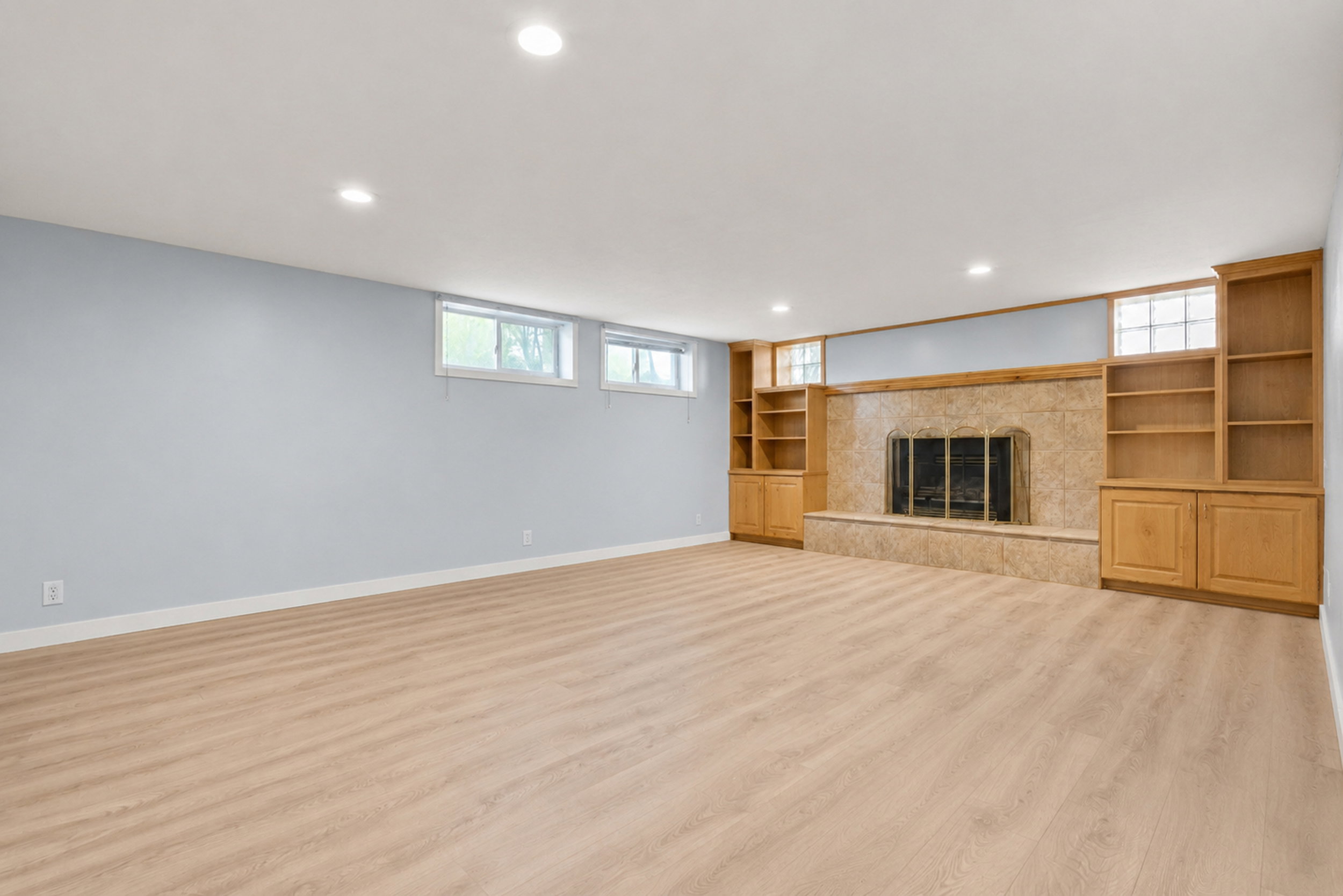 Spacious room featuring a stone-clad fireplace with a hearth, integrated shelving, and cabinetry