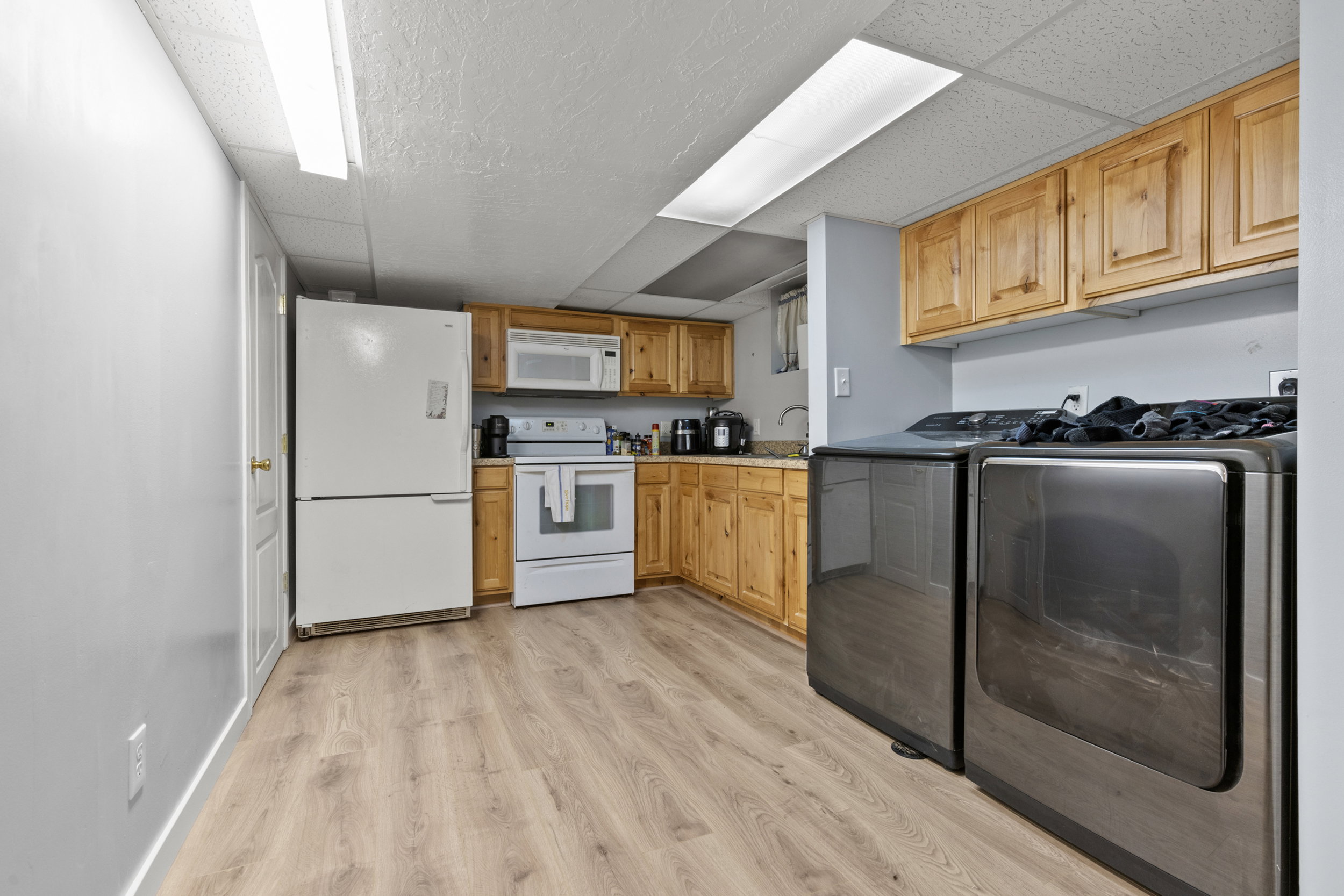Kitchenette featuring wood-finish cabinetry, light-toned countertops, and wood-finish flooring