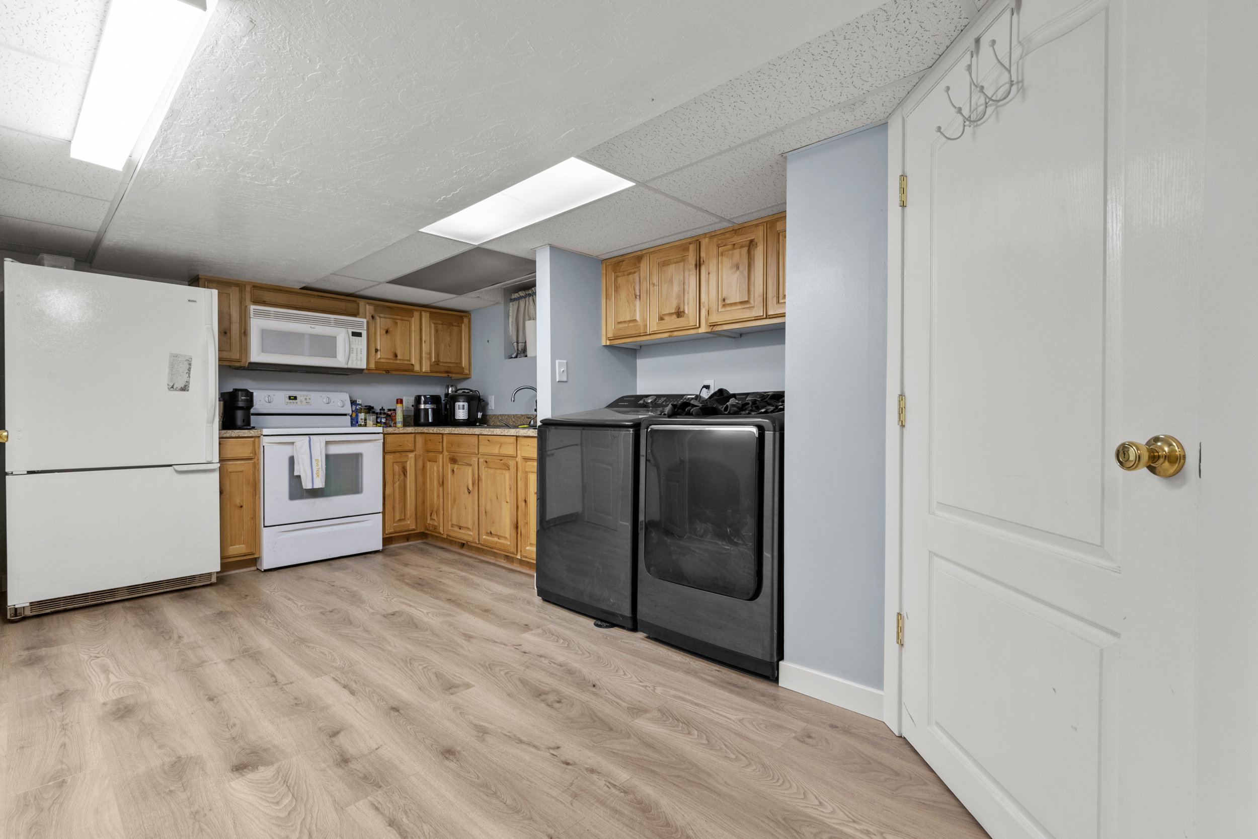 Kitchenette with light wood-finish cabinetry, dark countertops, and wood-look flooring