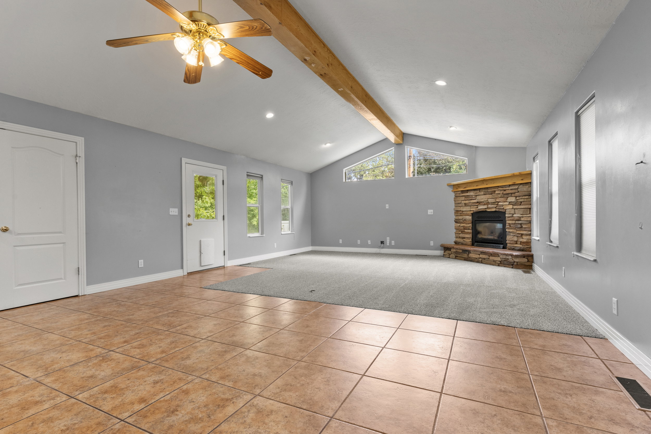Spacious living area featuring a vaulted ceiling with exposed wood beam, recessed lighting, and a ceiling fan