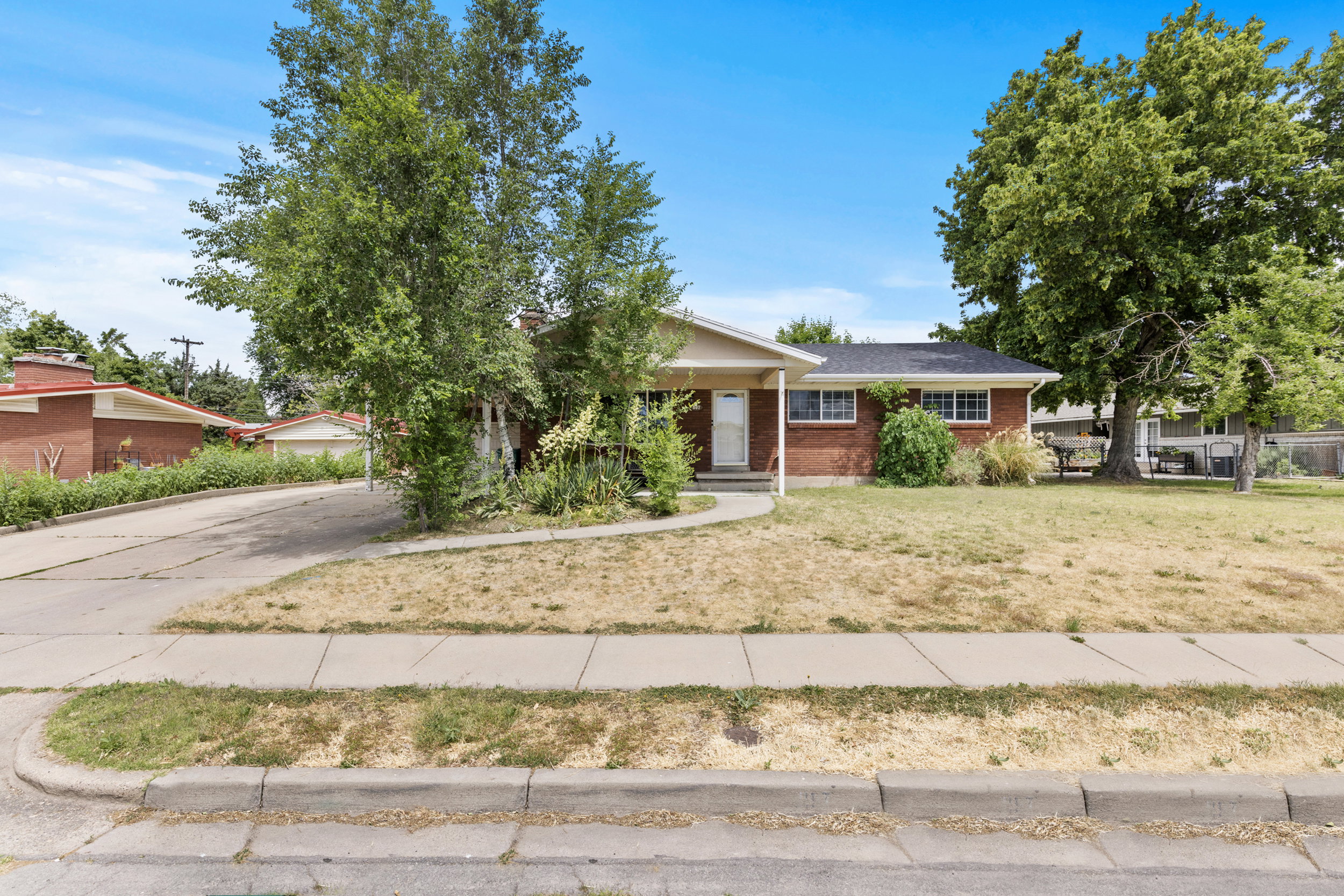 Brick exterior residence featuring a covered front entry, established landscaping, and a paved driveway