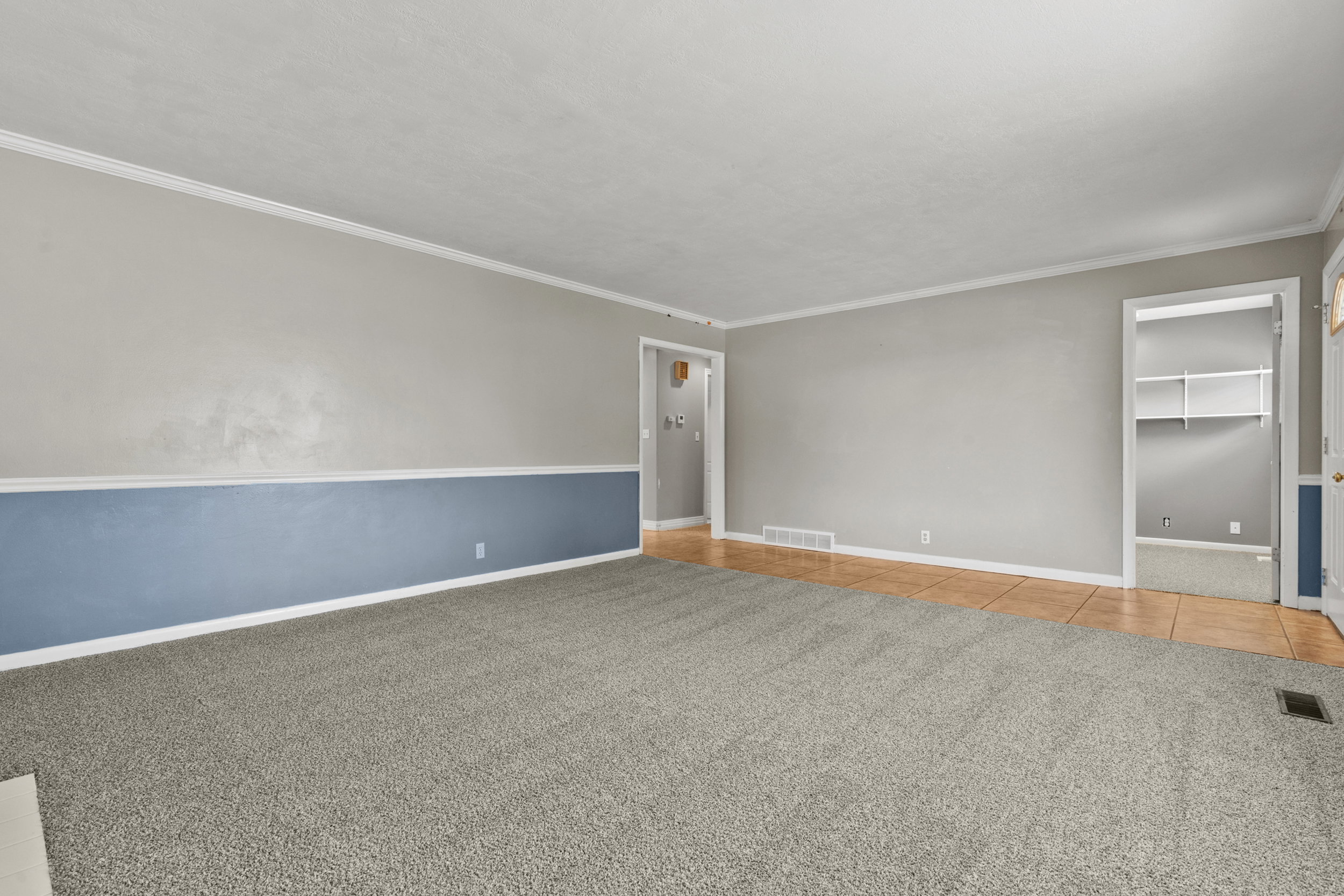 Spacious room with gray textured carpeting and a neutral wall color featuring a blue accent band