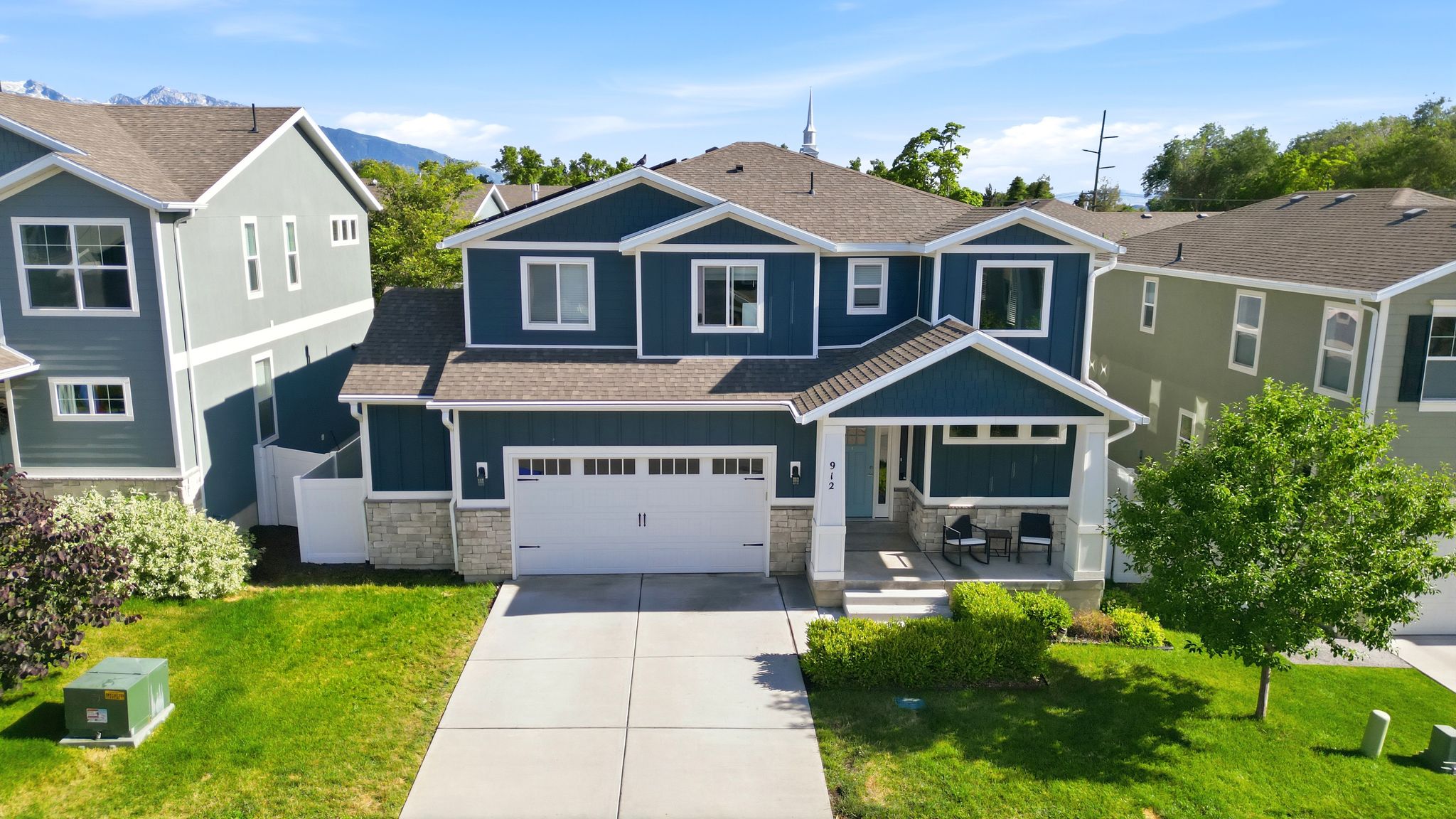 Contemporary two-story residence featuring a deep blue exterior with white trim, a stone accent foundation, and a covered front porch