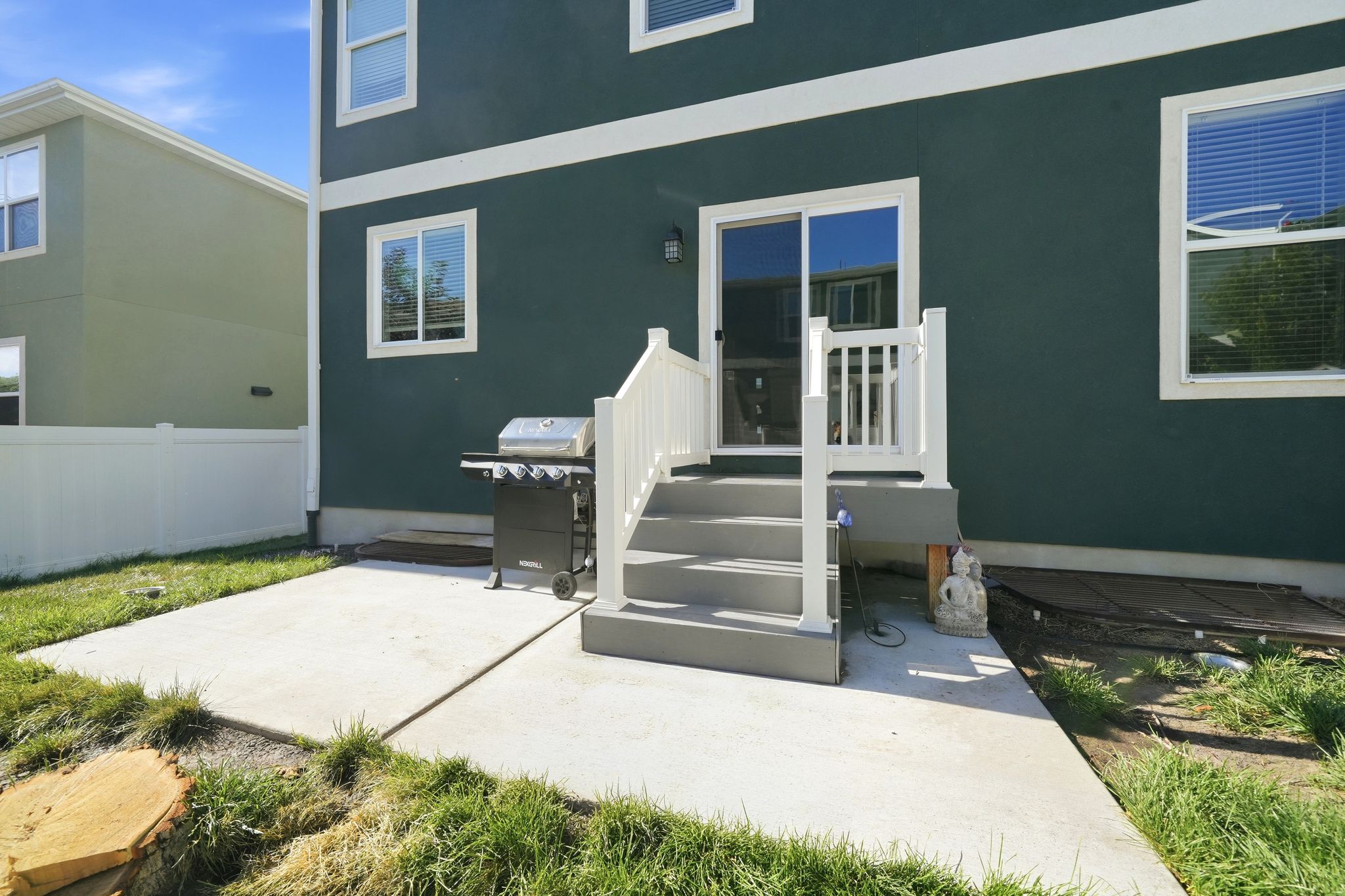 Rear exterior featuring a sliding glass door, private patio, exterior lighting, and white window trim