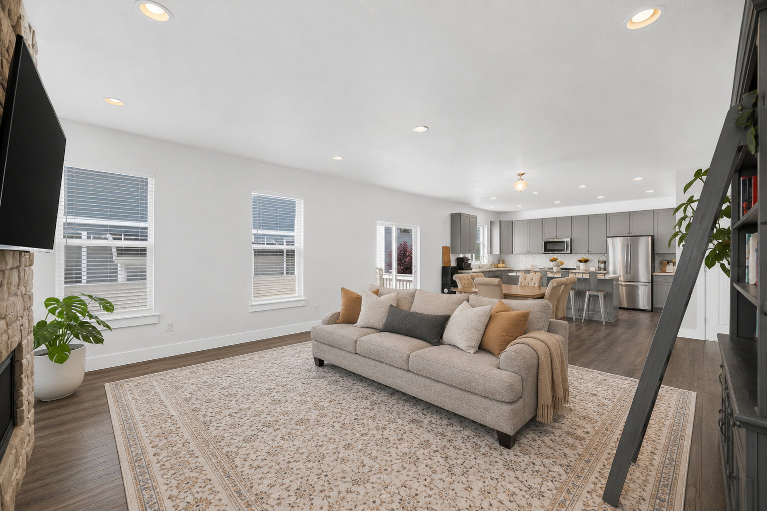 Open-concept living space featuring wood-finish flooring, recessed lighting, and a stone-clad fireplace