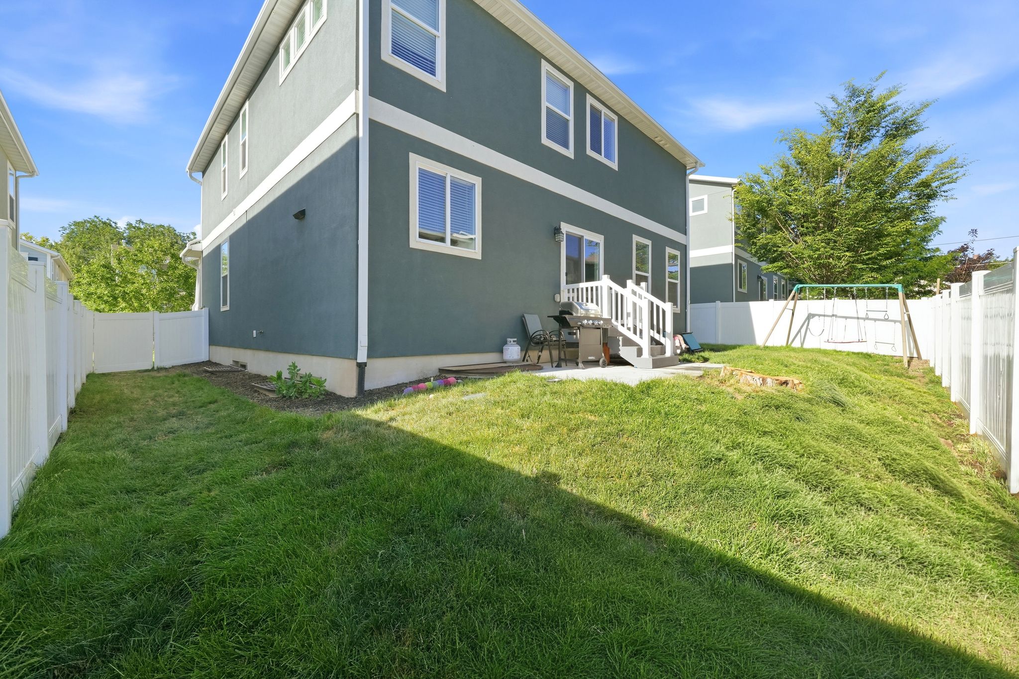 Rear exterior featuring a two-story stucco facade, white trim, and a private fenced yard