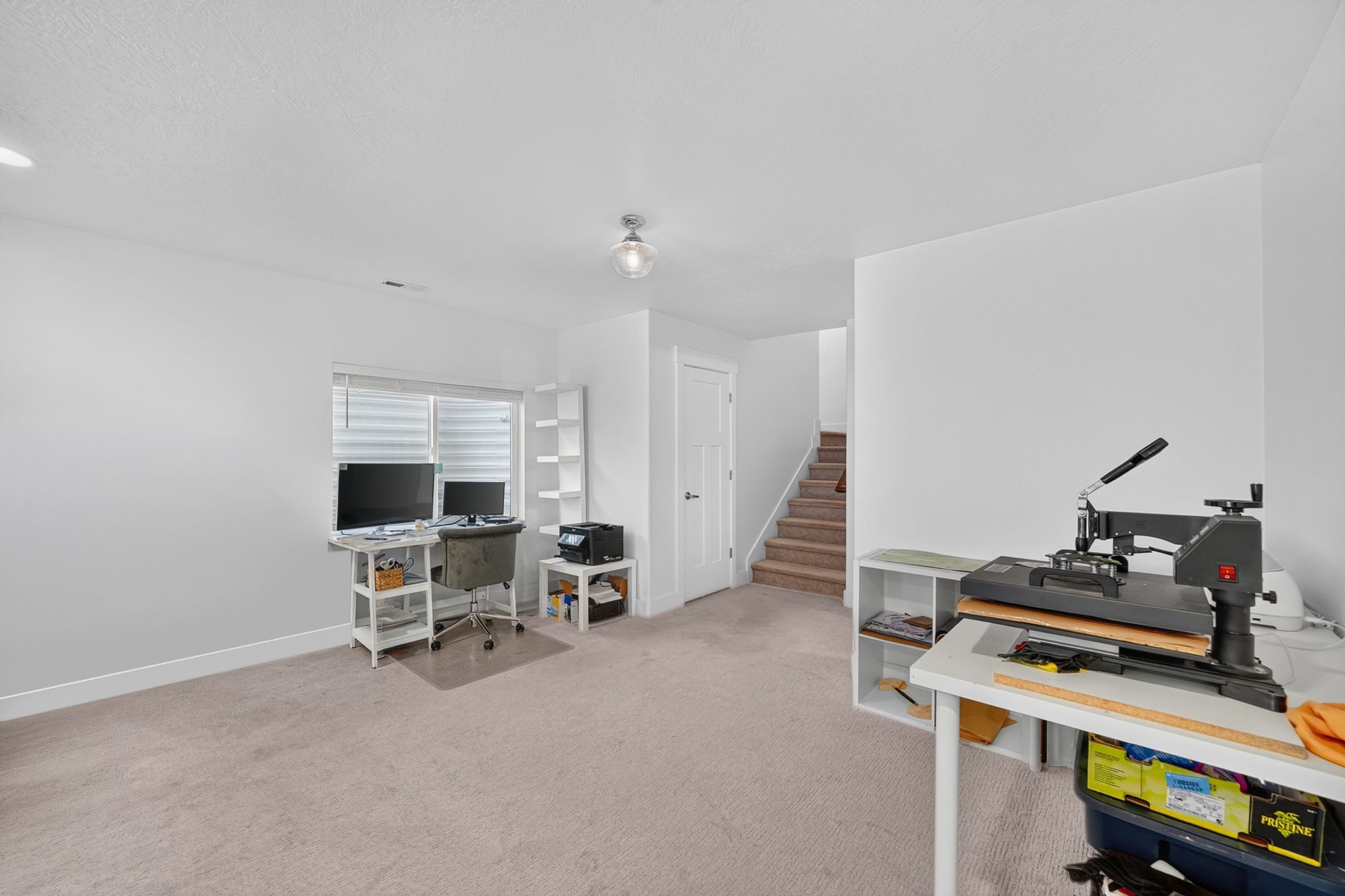 Spacious room featuring neutral carpeting, white walls, and a window with horizontal blinds