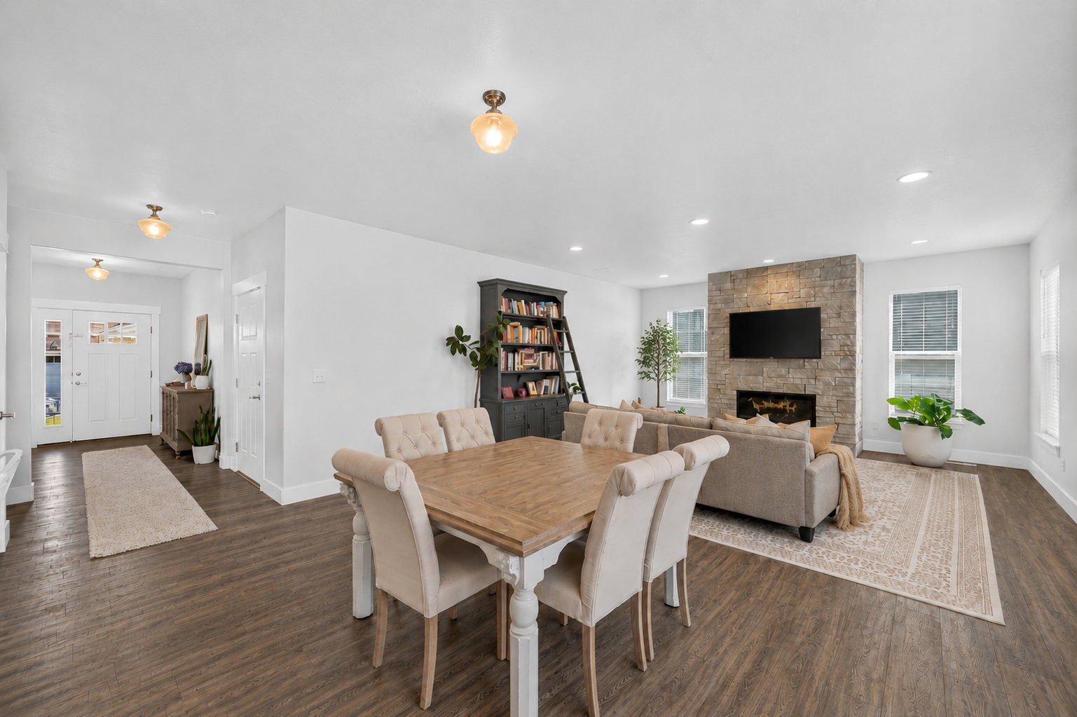 Open-concept living space featuring wood-finish flooring, recessed lighting, and a stone-clad fireplace