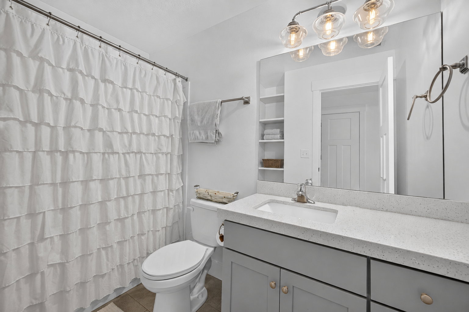 Bathroom featuring a single vanity with a light gray cabinet, a white countertop, and an undermount sink