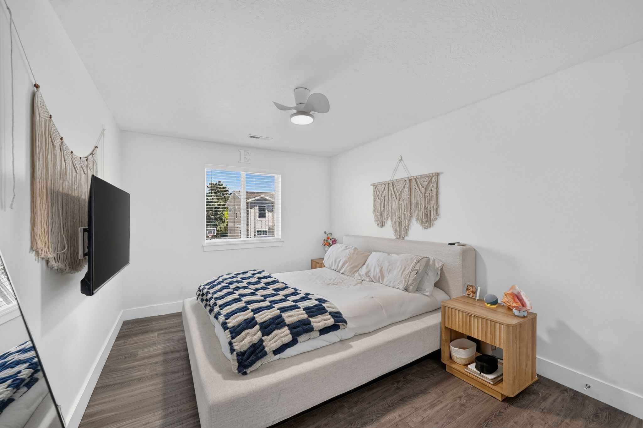 Bright room featuring wood-finish flooring, a white ceiling fan with integrated lighting, and a window with blinds