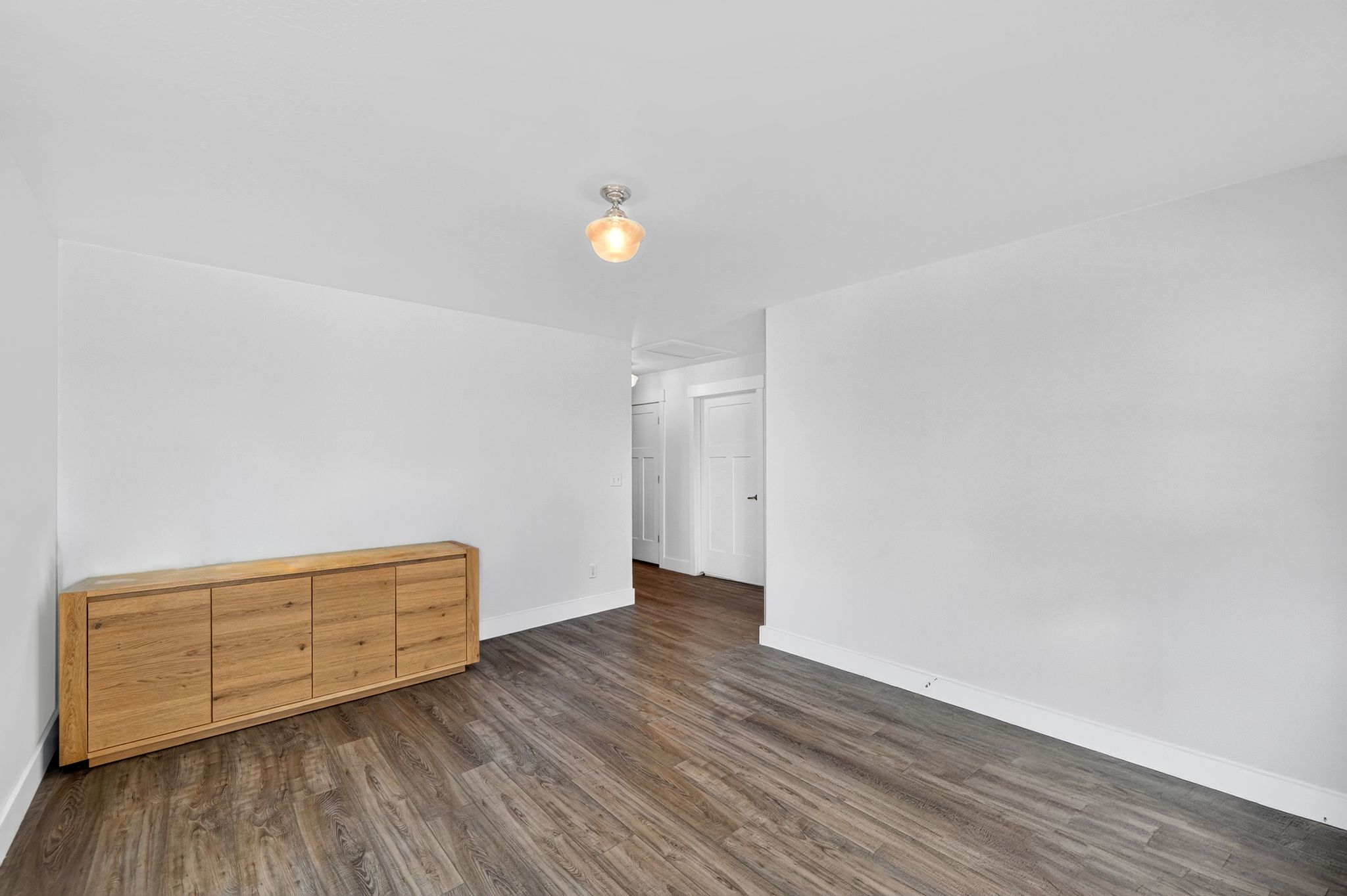 Expansive room featuring wood-finish flooring, white walls, and a ceiling-mounted light fixture