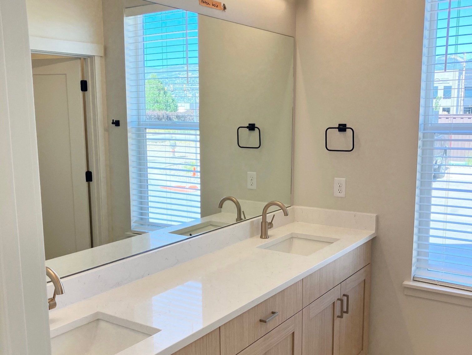 Dual vanity featuring light wood-finish cabinetry, brushed nickel hardware, and a white countertop with integrated sinks