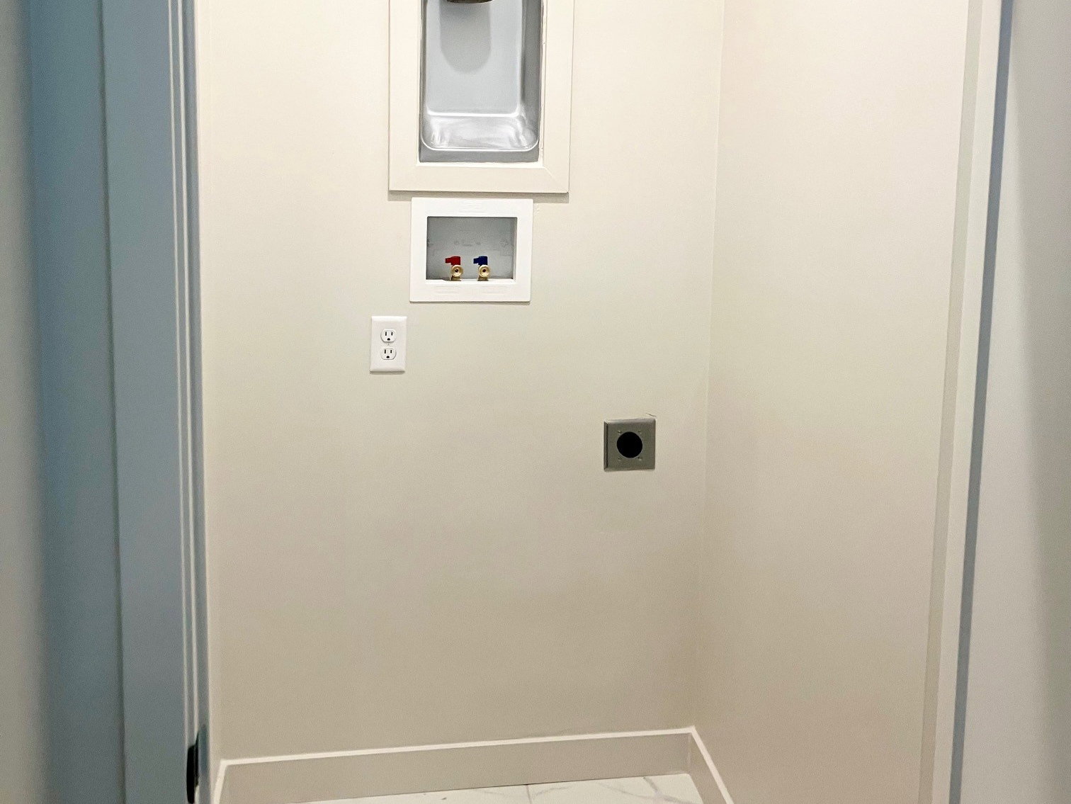 Dedicated laundry area featuring marble-look tile flooring, light neutral wall paint, and white baseboards