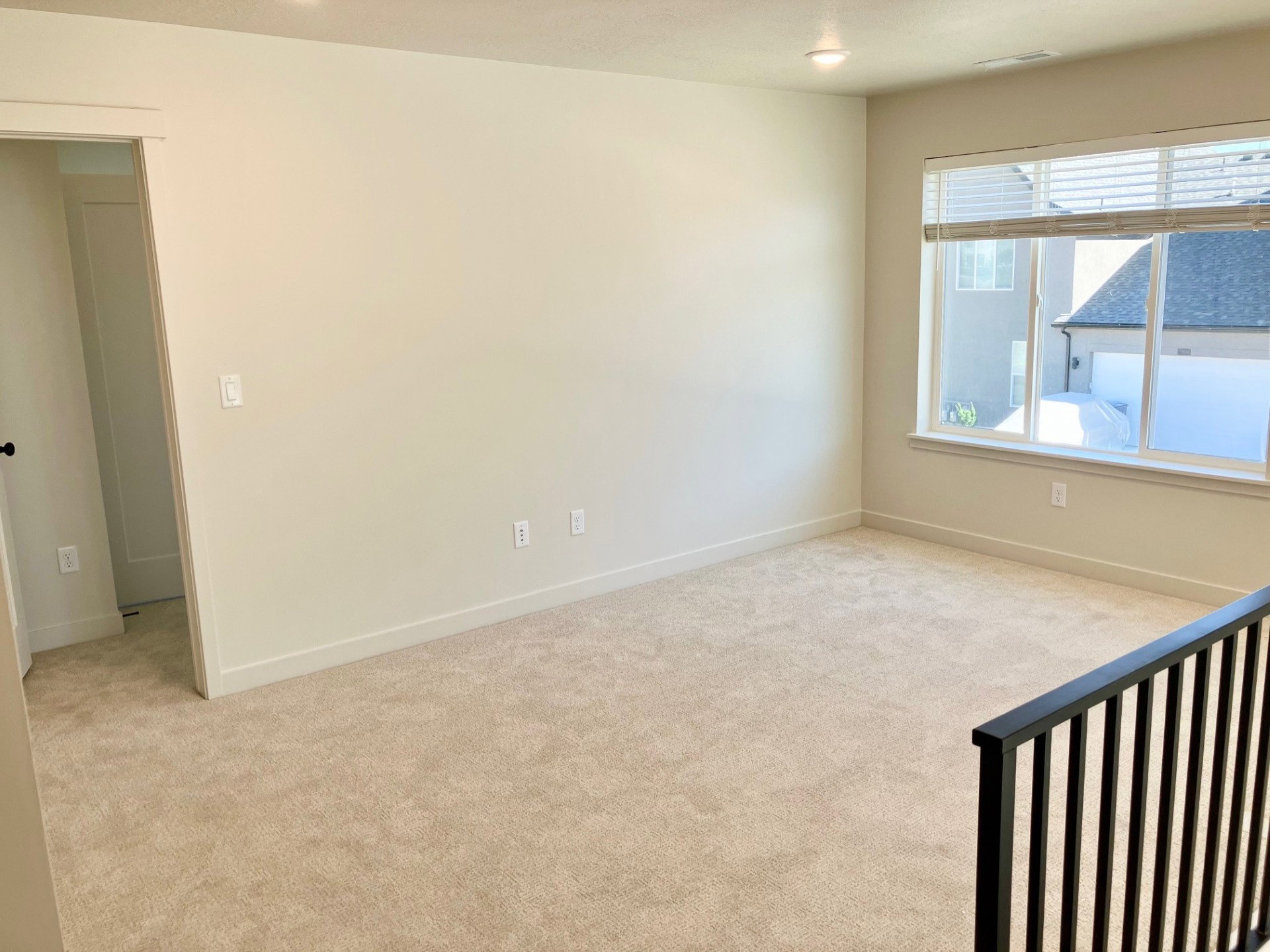 Carpeted room featuring a large window with blinds, recessed lighting, and a doorway