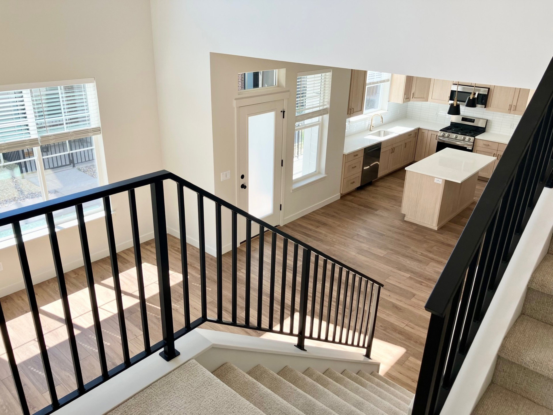 Open-concept living space featuring wood-finish flooring, a contemporary kitchen with light cabinetry, a central island, and stainless steel appliances