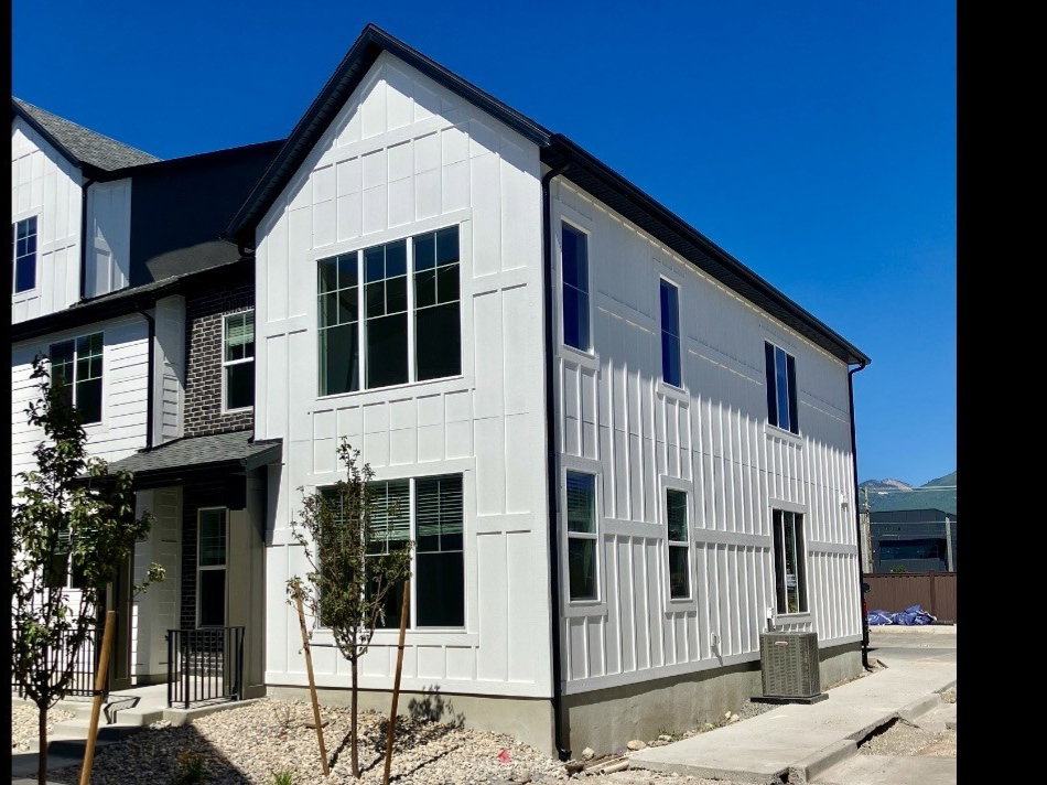Contemporary exterior featuring white board and batten siding, black trim accents, and multiple large windows