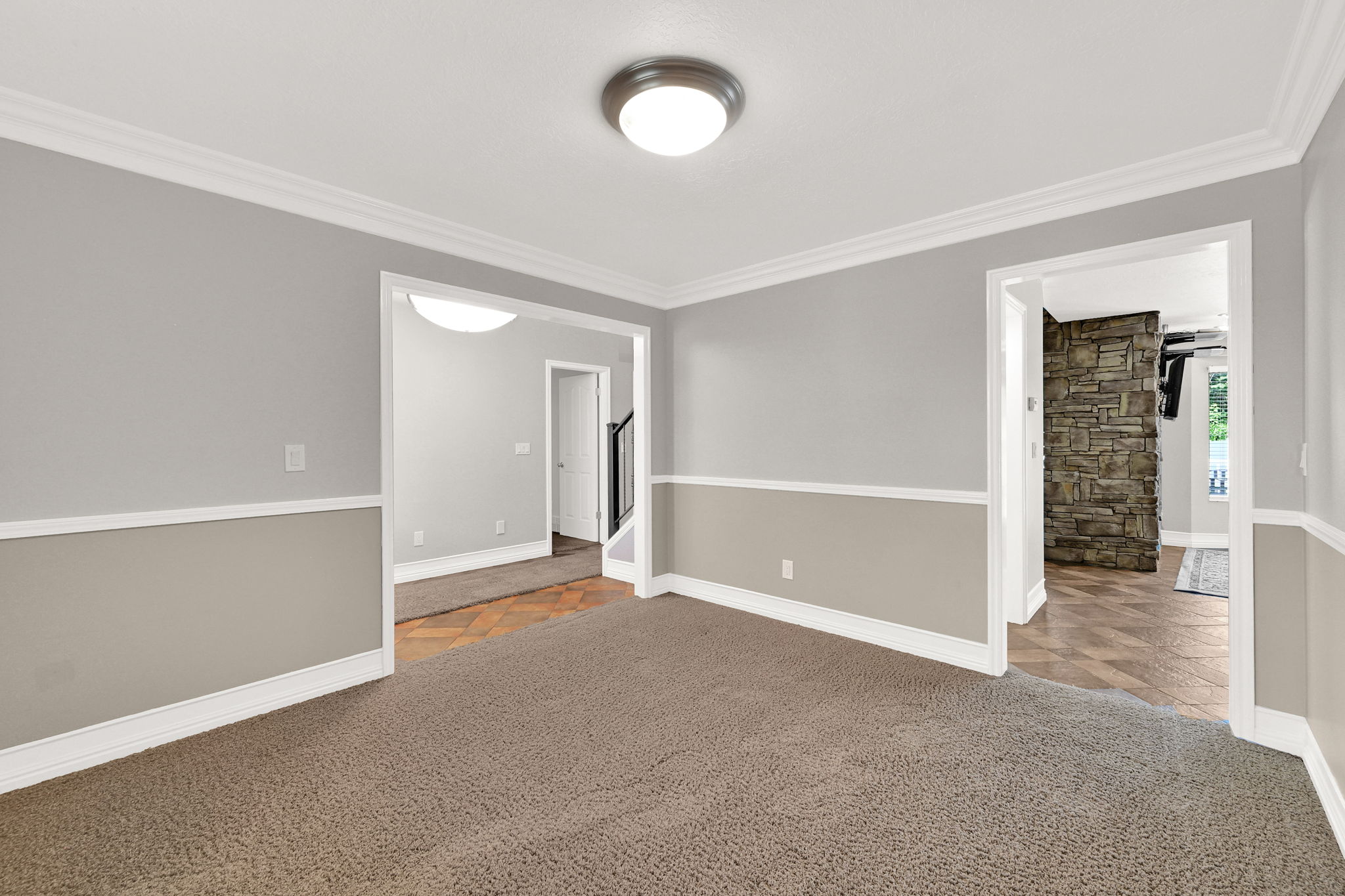 Neutral toned interior space featuring carpet flooring and crown molding with views into the entrance way and kitchen area