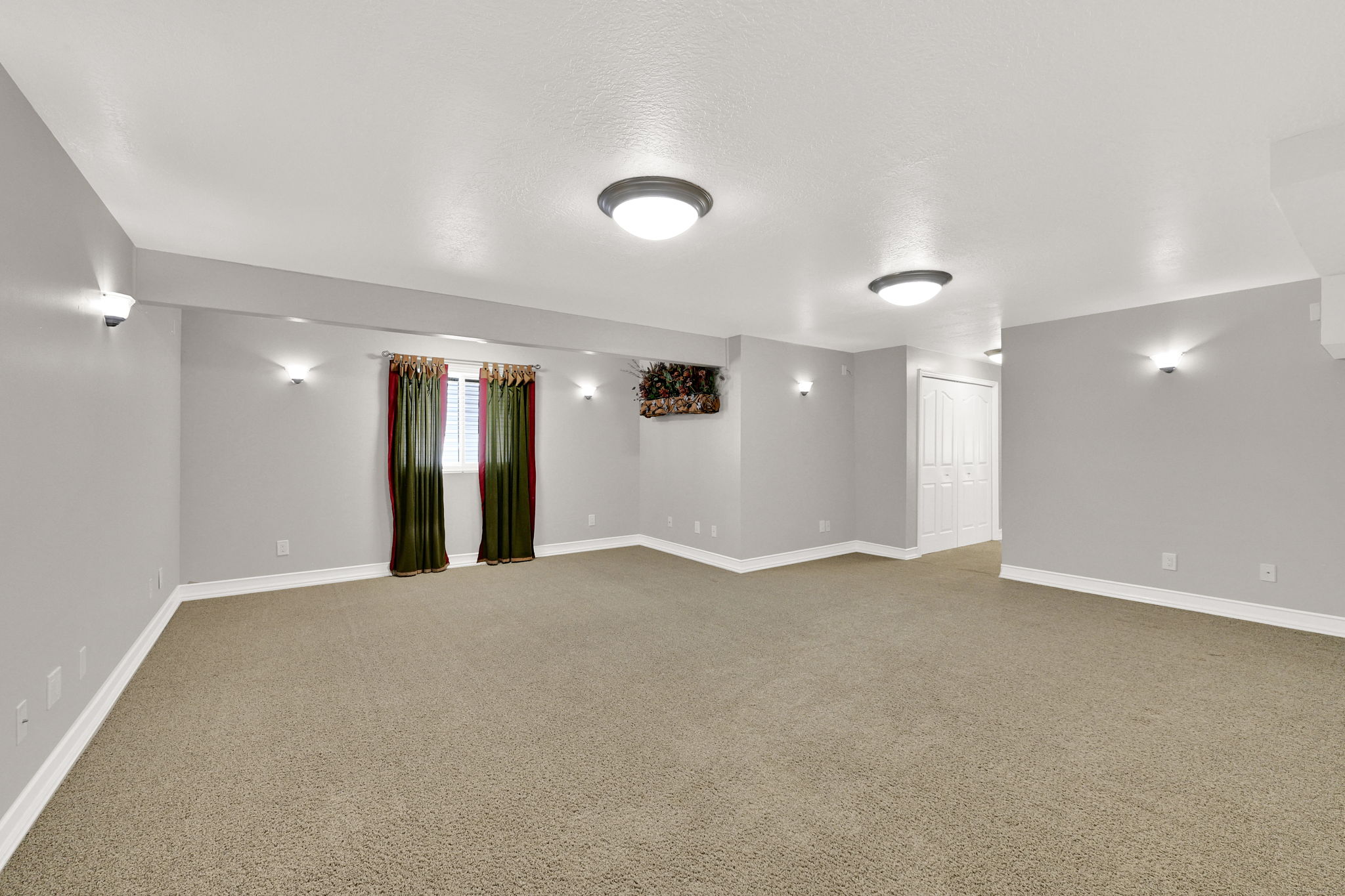 Spacious room featuring neutral carpeting and light gray walls with lots of natural light