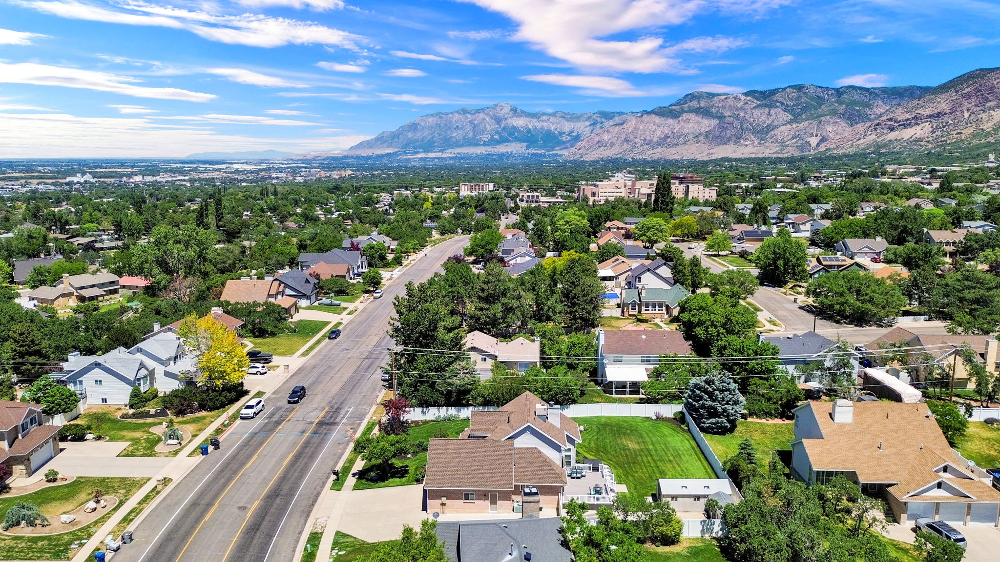 Aerial perspective showcasing a residential area with custom home styles, mature landscaping, and mountainous terrain in the background