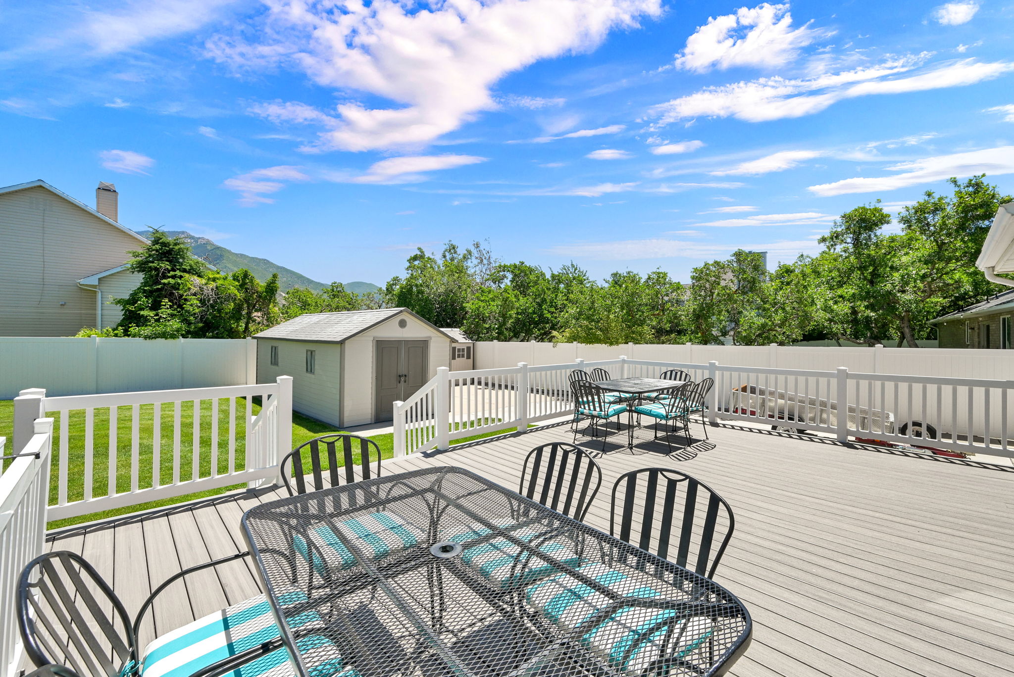 Spacious outdoor deck featuring composite decking, white railing with gate to hot tub, and stairs to a fenced yard