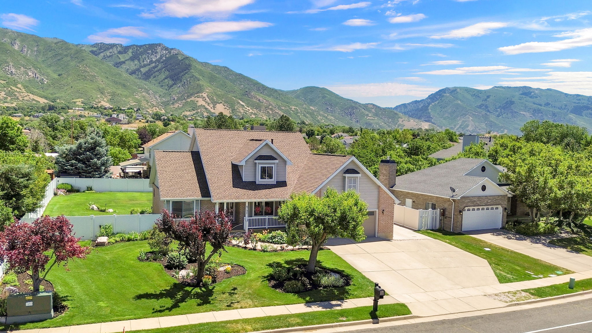 Two-story residence featuring a covered front porch, dormer windows, and a paved driveway