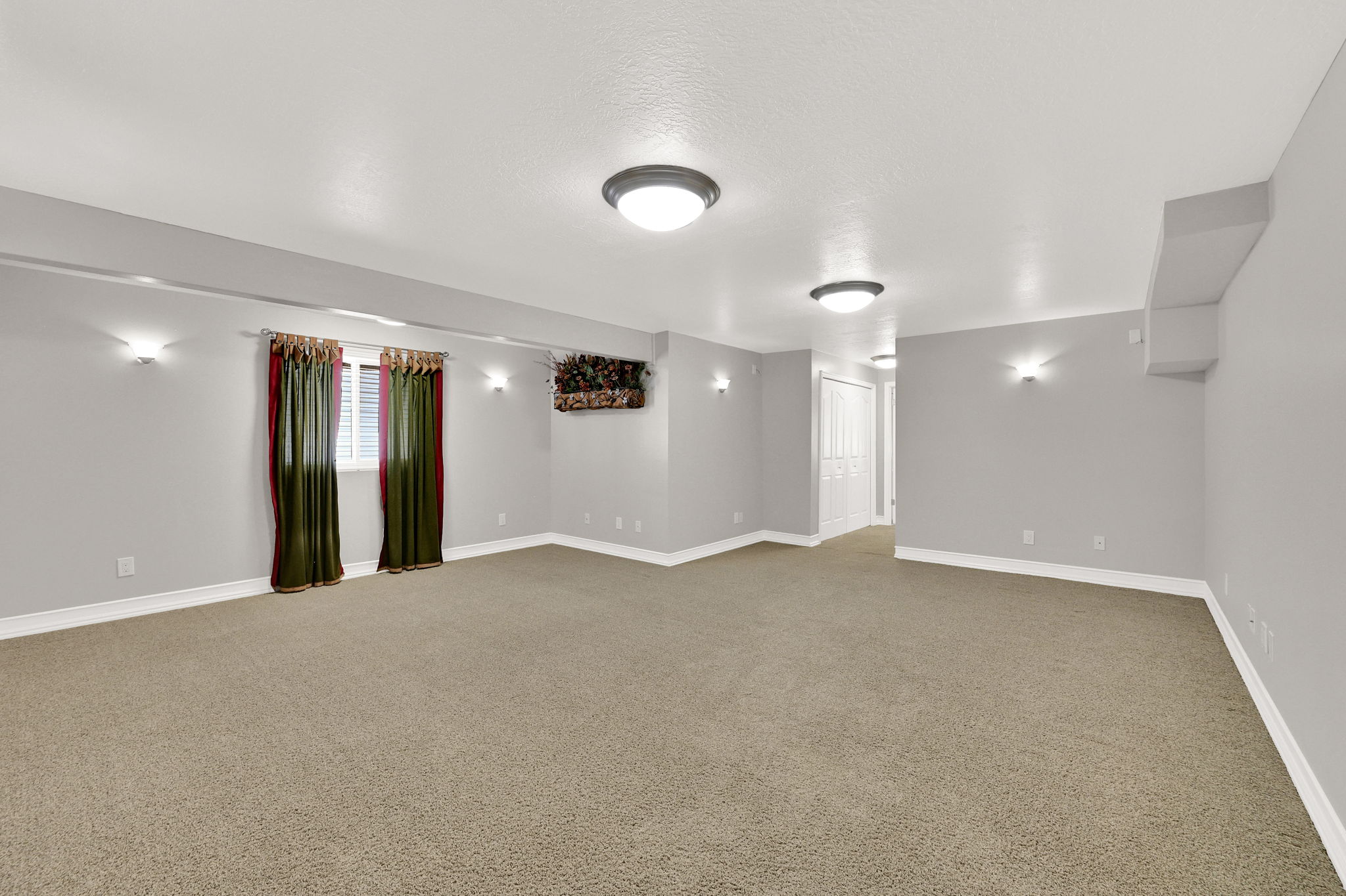 Spacious room featuring neutral carpeting, light gray walls, white trim, and recessed lighting