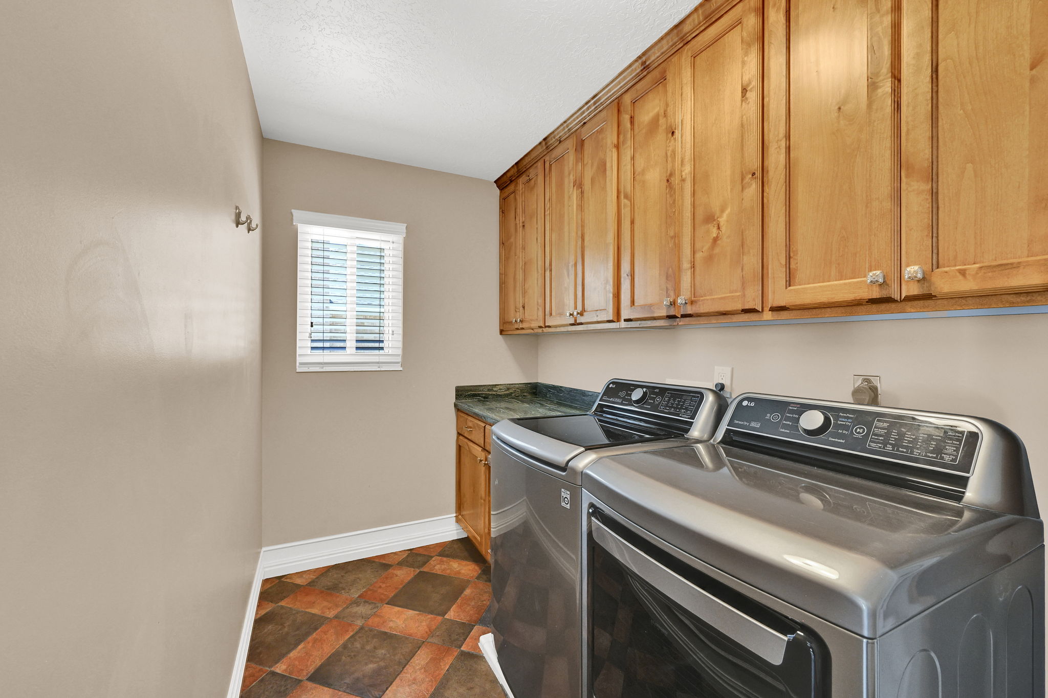 Utility area featuring abundant wood cabinetry, a dark countertop, and tiled flooring