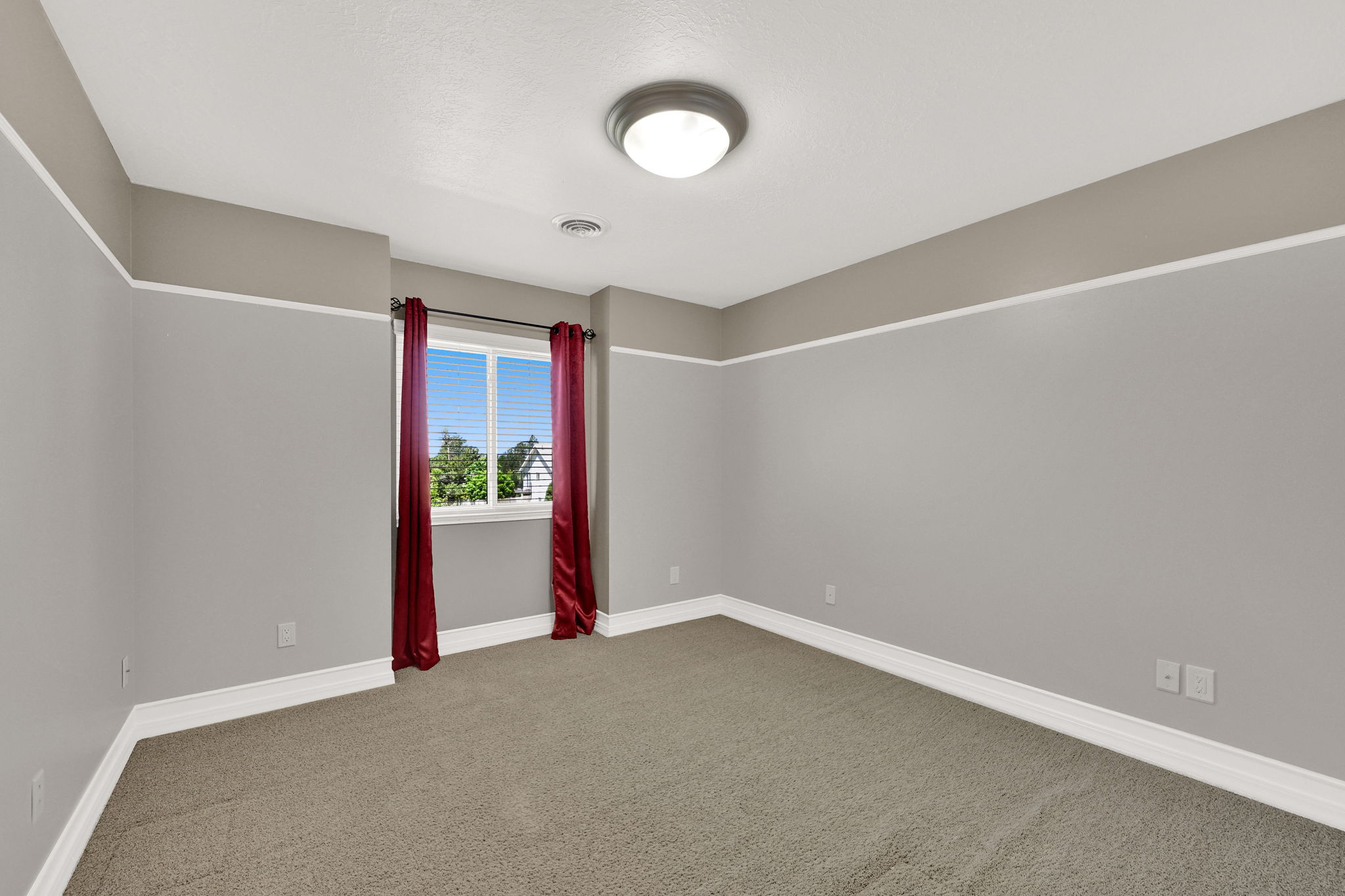 Bedroom #2 carpeted and featuring a double window, white baseboards, and a neutral wall color with white trim detailing