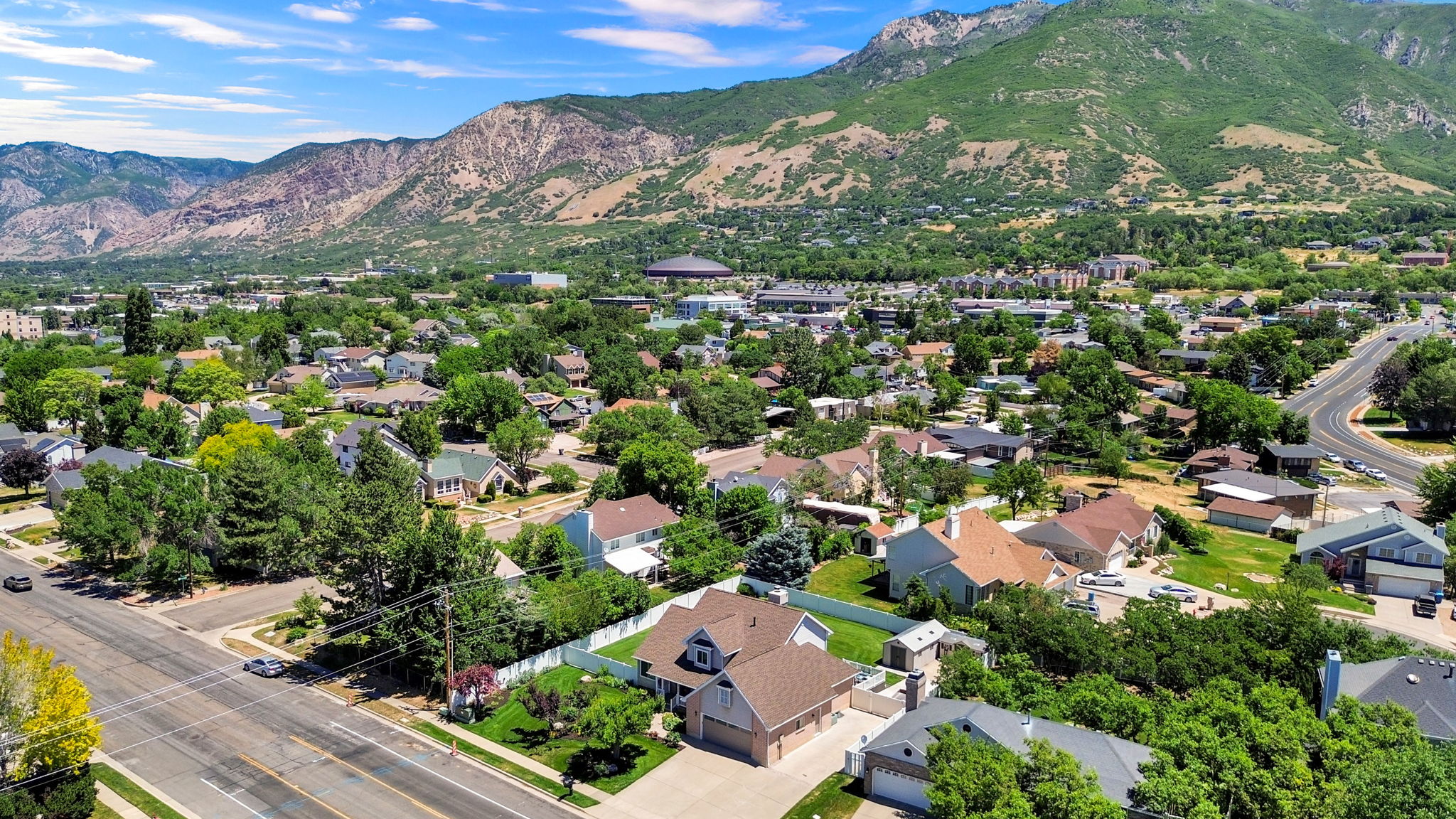 Residential neighborhood with mature trees, mountain backdrop, and paved roads