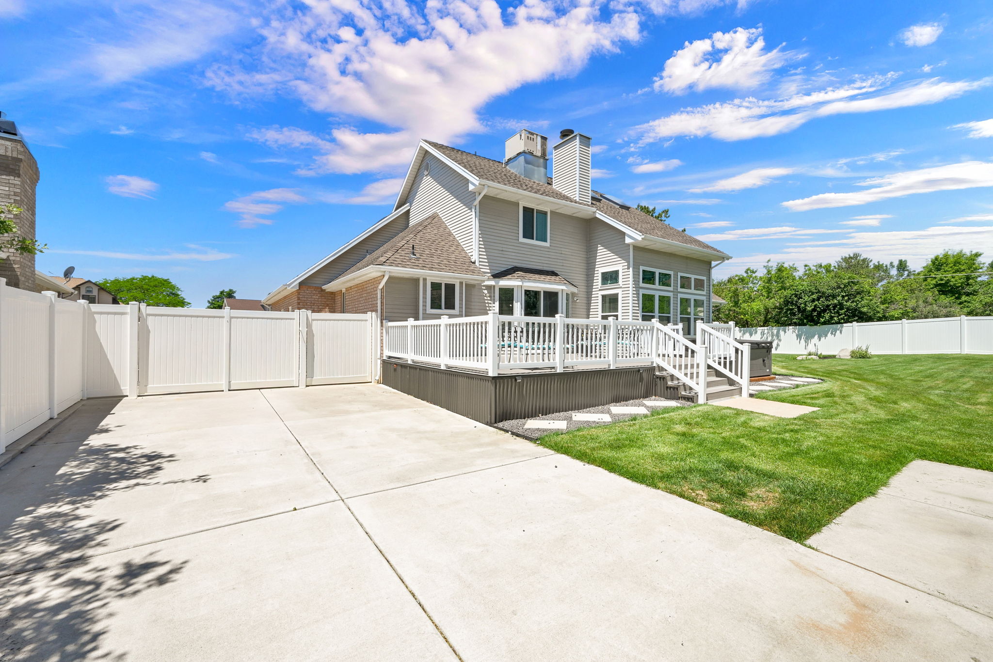 Expansive concrete driveway with privacy fencing with large drive through gate and a spacious rear deck