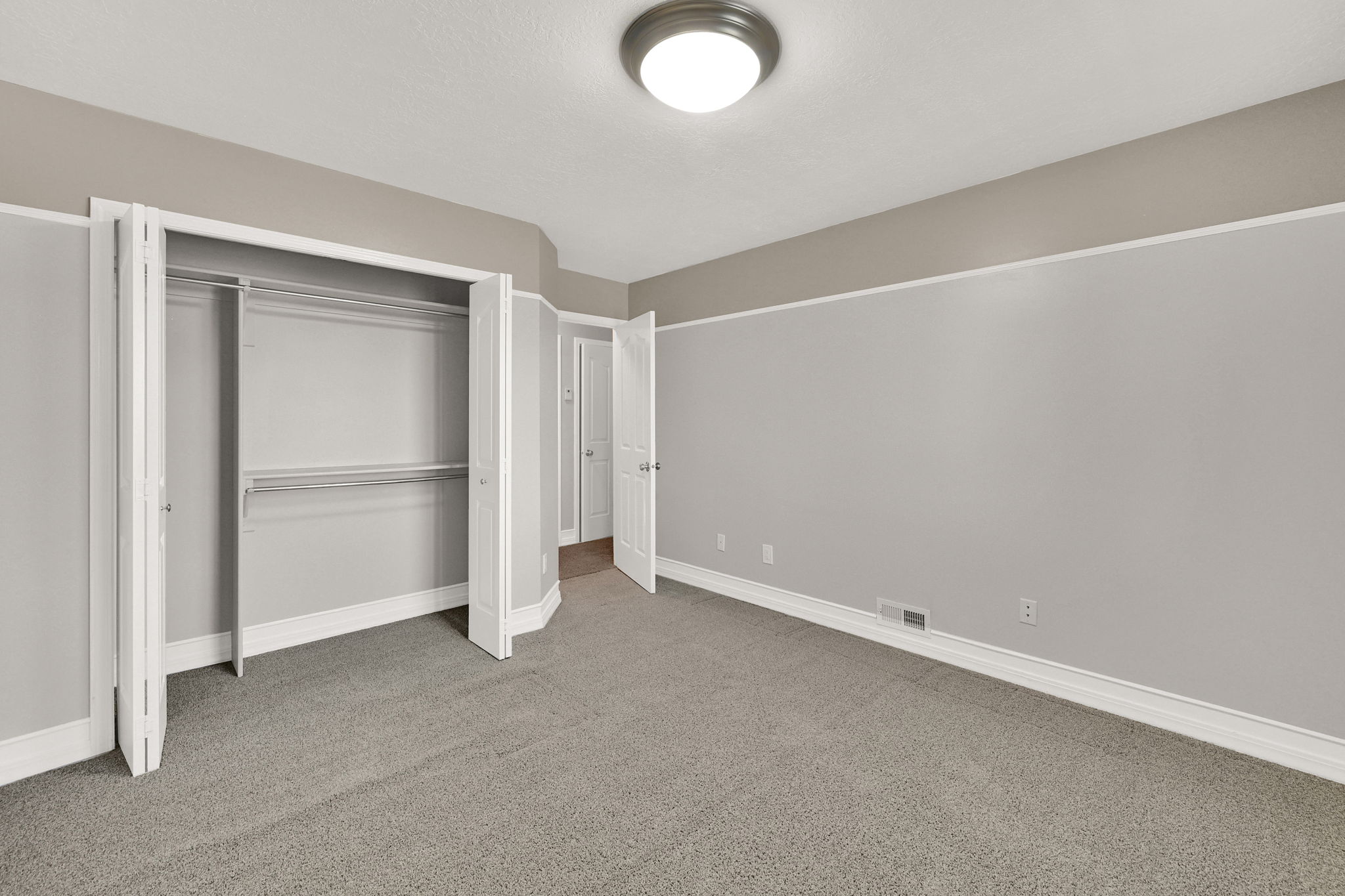 Bedroom #2 interior room featuring neutral gray carpeting and light gray walls with a beige accent band and custom shelving