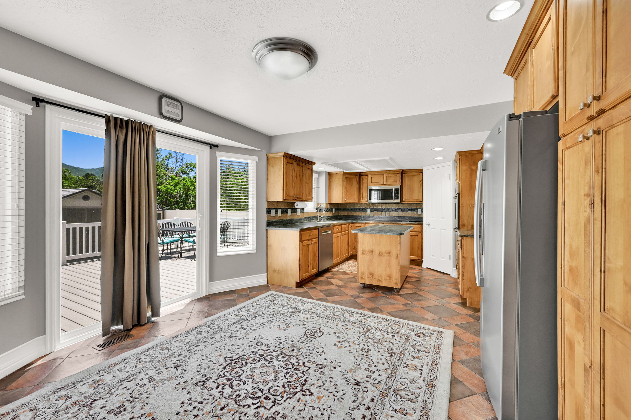 Kitchen with wood cabinetry, stainless steel appliances, and a central castor wheeled island with countertop