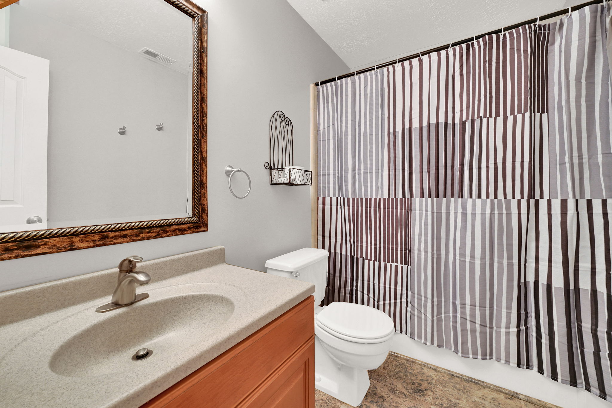 Full bathroom featuring a vanity with an integrated sink, wood-finish cabinetry, a framed wall mirror, and a toilet