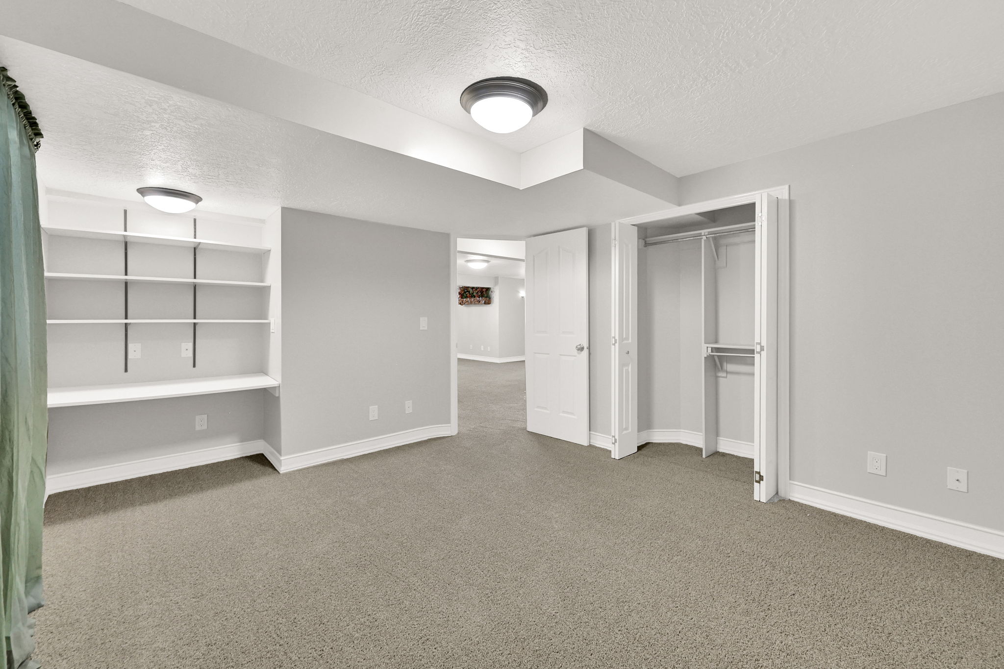 Bedroom #4 spacious room featuring neutral carpeting, desk and built-in shelving, and a double-door closet with custom shelving and hanging rods