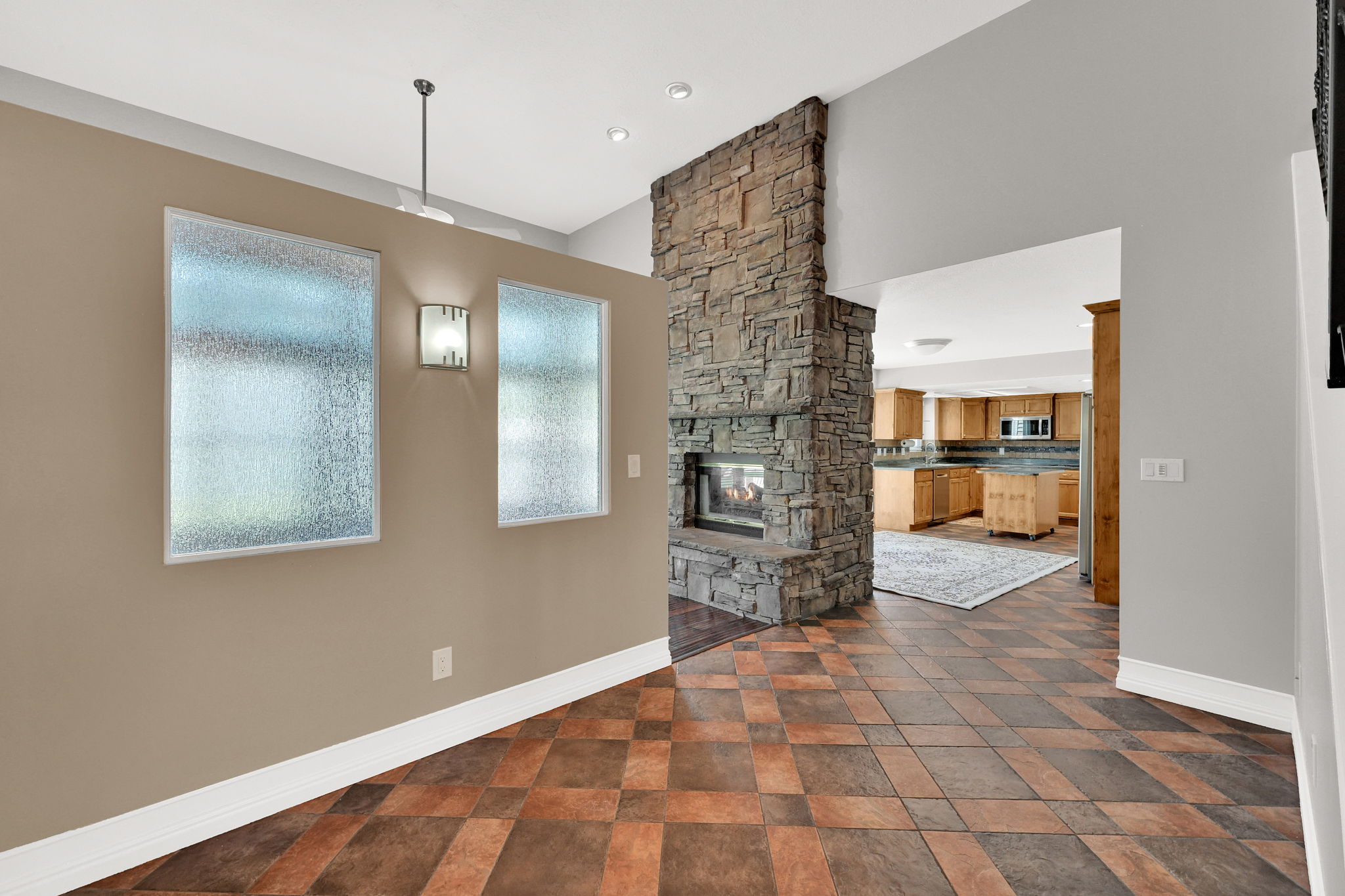 Stone fireplace with hearth, tile flooring, recessed lighting, and frosted windows