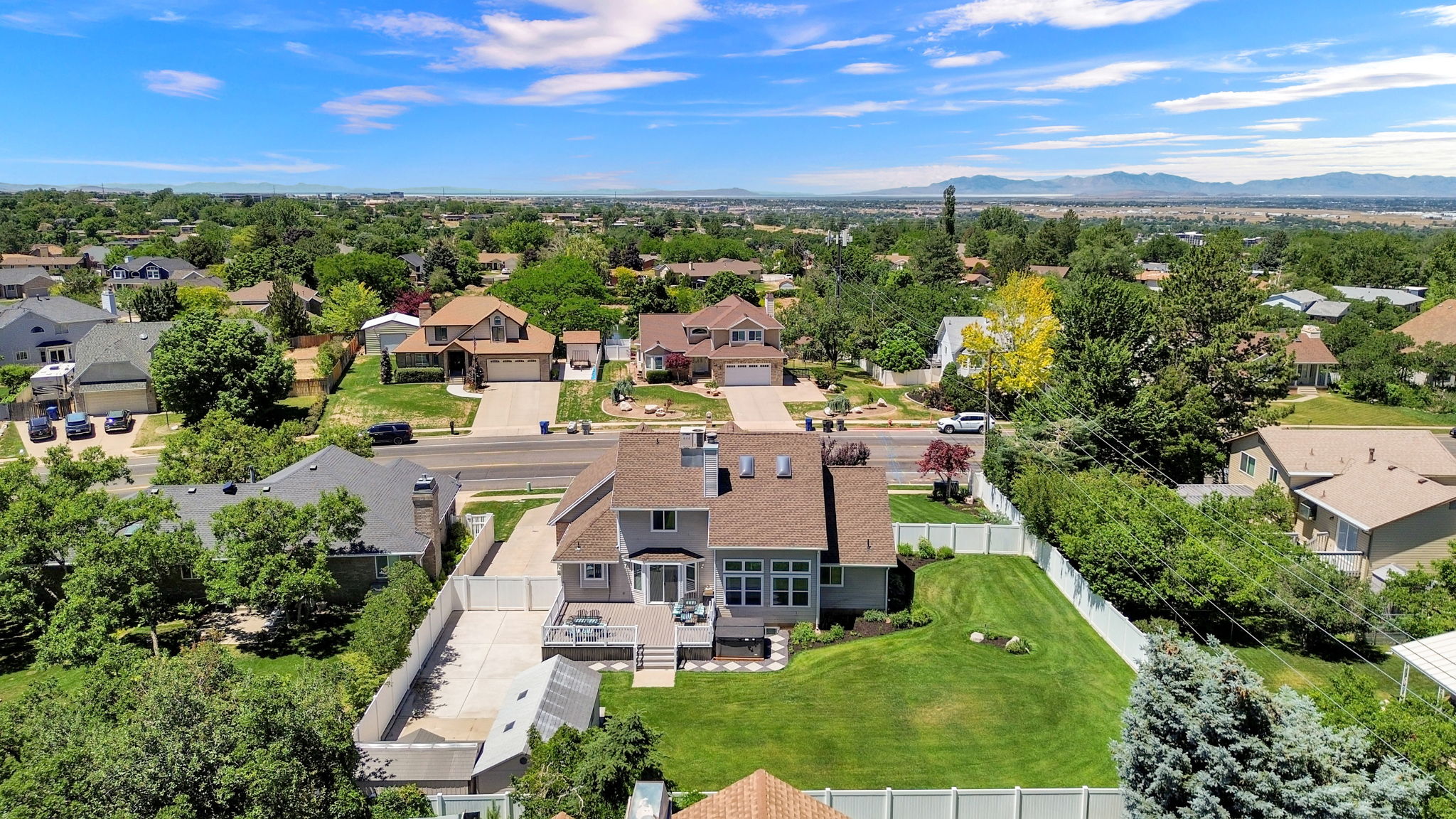 Expansive property featuring a large landscaped lawn, white privacy fencing, and mature trees