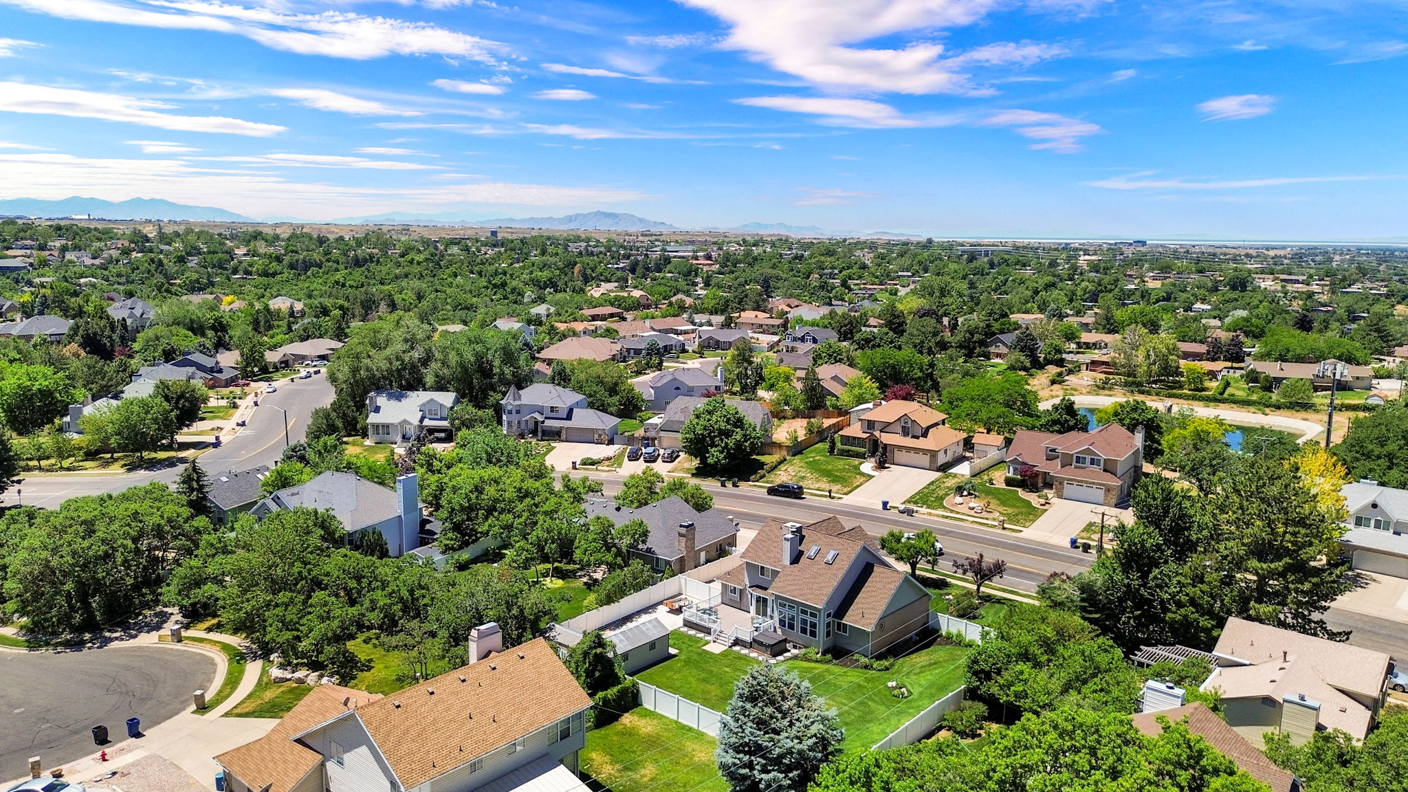 Spacious residential property featuring a large backyard with a white privacy fence and mature trees