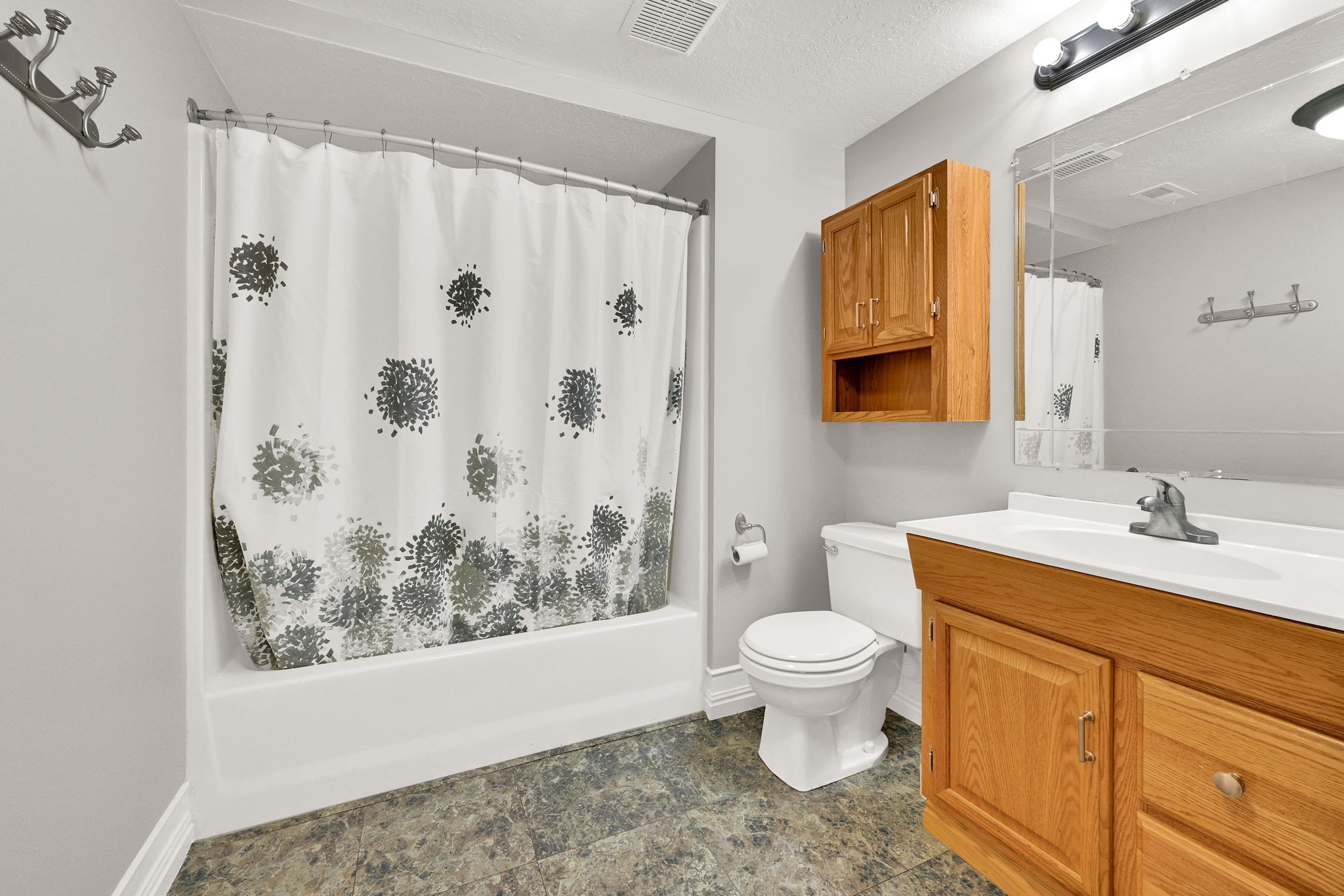 Full bathroom featuring a single vanity with wood-finish cabinetry including a medicine cabinet, a white basin, and a mirror