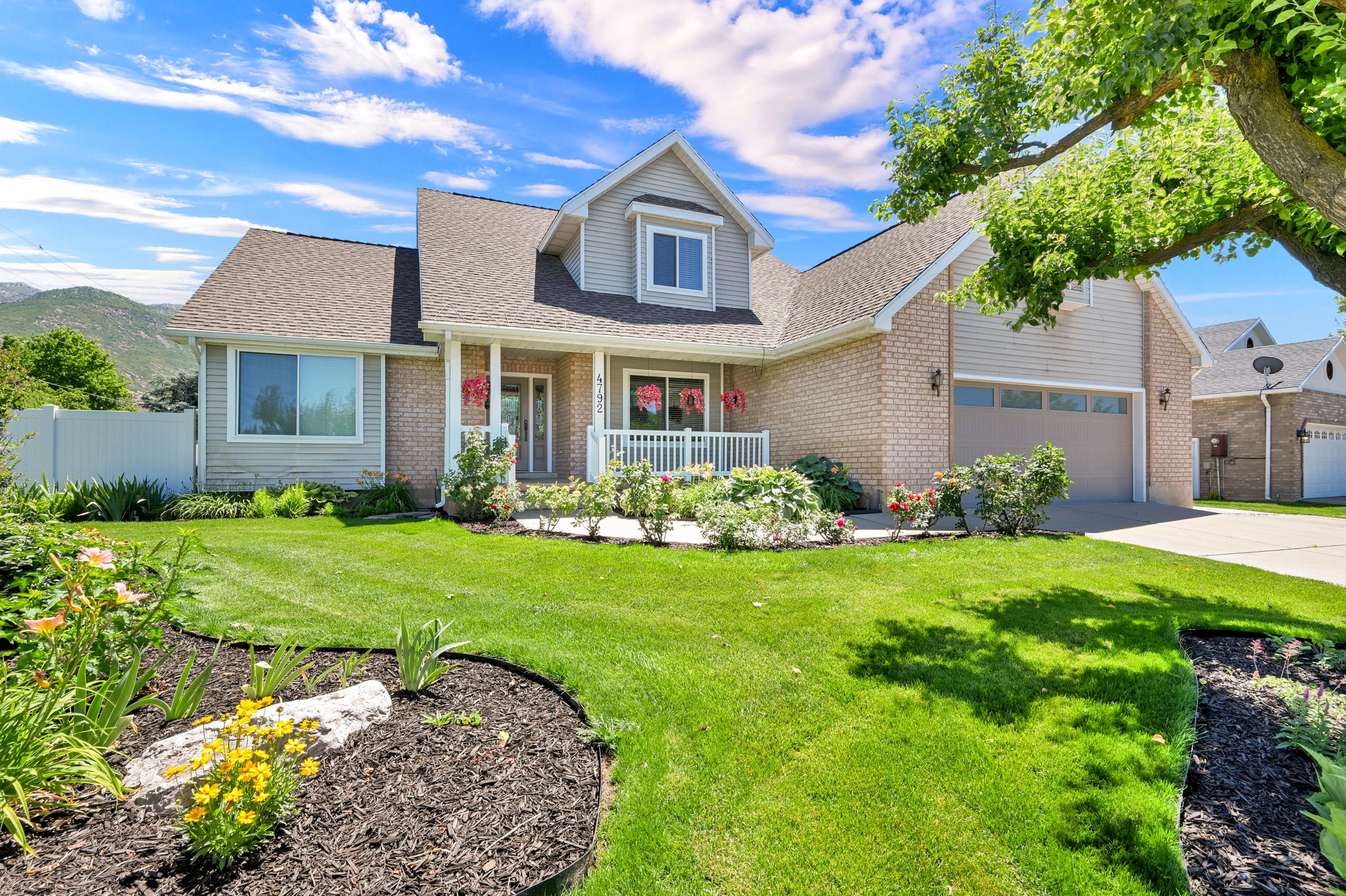 Brick and siding exterior featuring a covered front porch, white railing, and a two-car garage