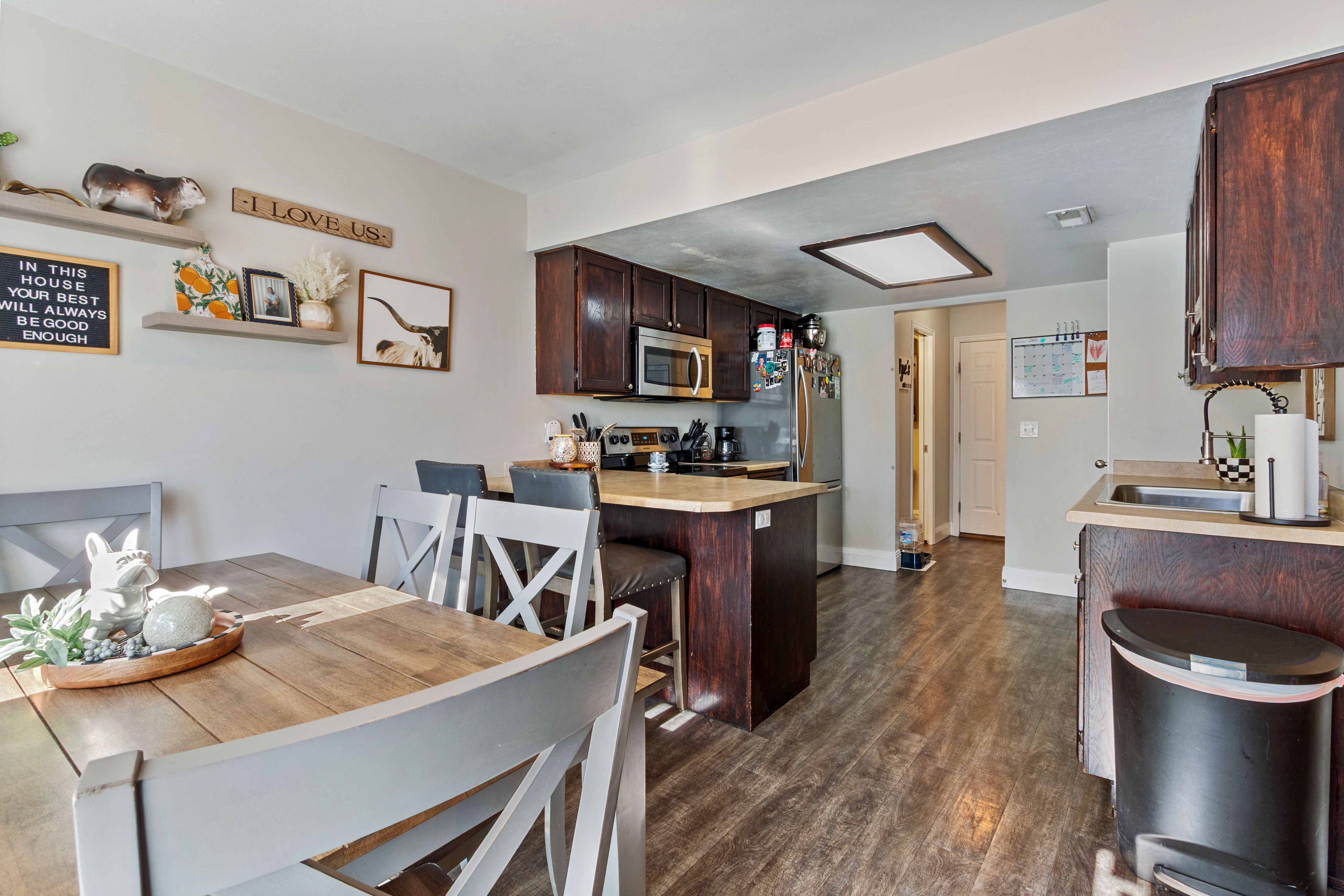 Kitchen featuring dark wood cabinetry, stainless steel appliances, a center island with bar seating, and light-toned countertops