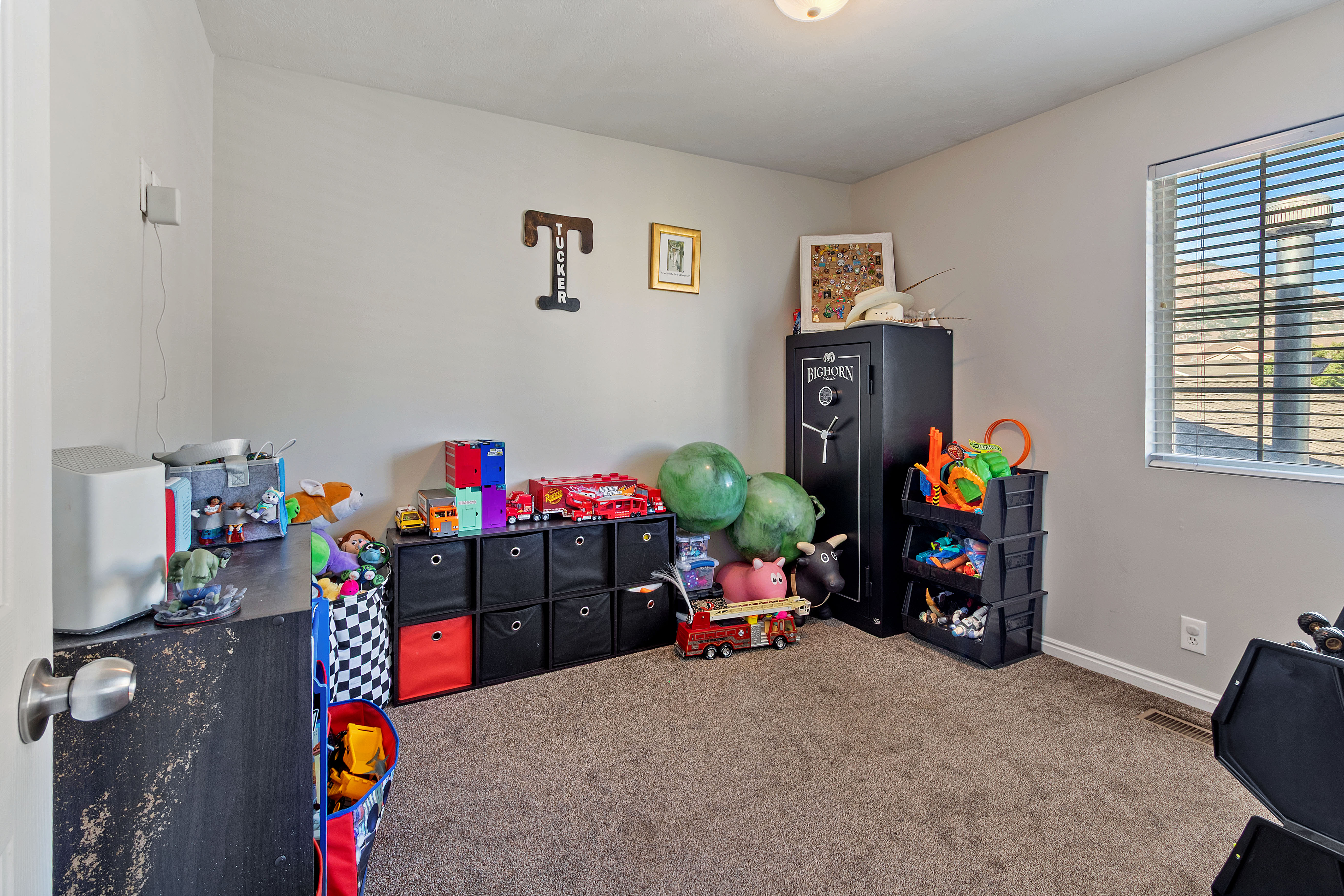 Carpeted interior room with neutral wall tones and a single window with blinds